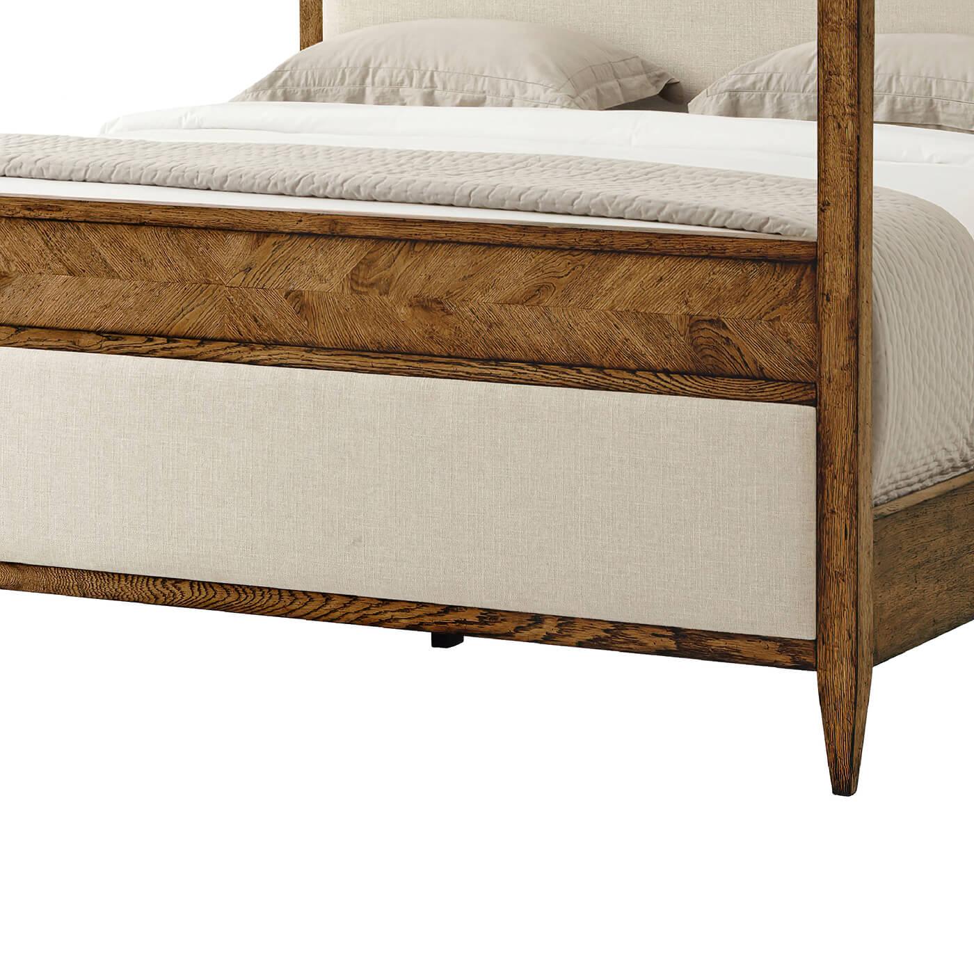 A modern rustic canopy California king bed crafted from oak with a Dusk finish. This beautifully designed bed has hand-carved oak solids and mirrored herringbone parquetry details blended with an upholstered panel on the headboard and footboard. It