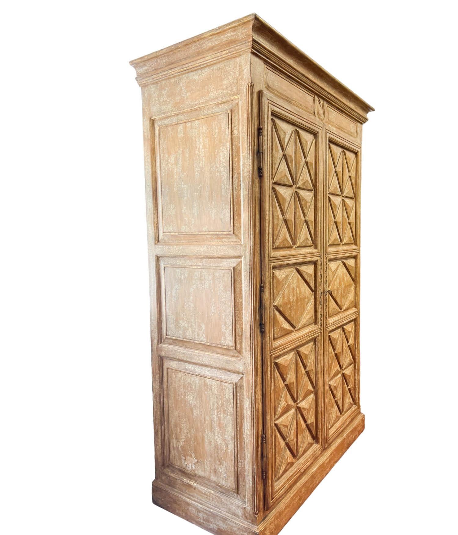 A Large-Scale Rustic-Inspired Armoire, a versatile and visually striking piece that effortlessly blends rustic charm with modern esthetics. The armoire's 3D paneled exterior is finished in a crackled paint technique, accentuated by gold leaf
