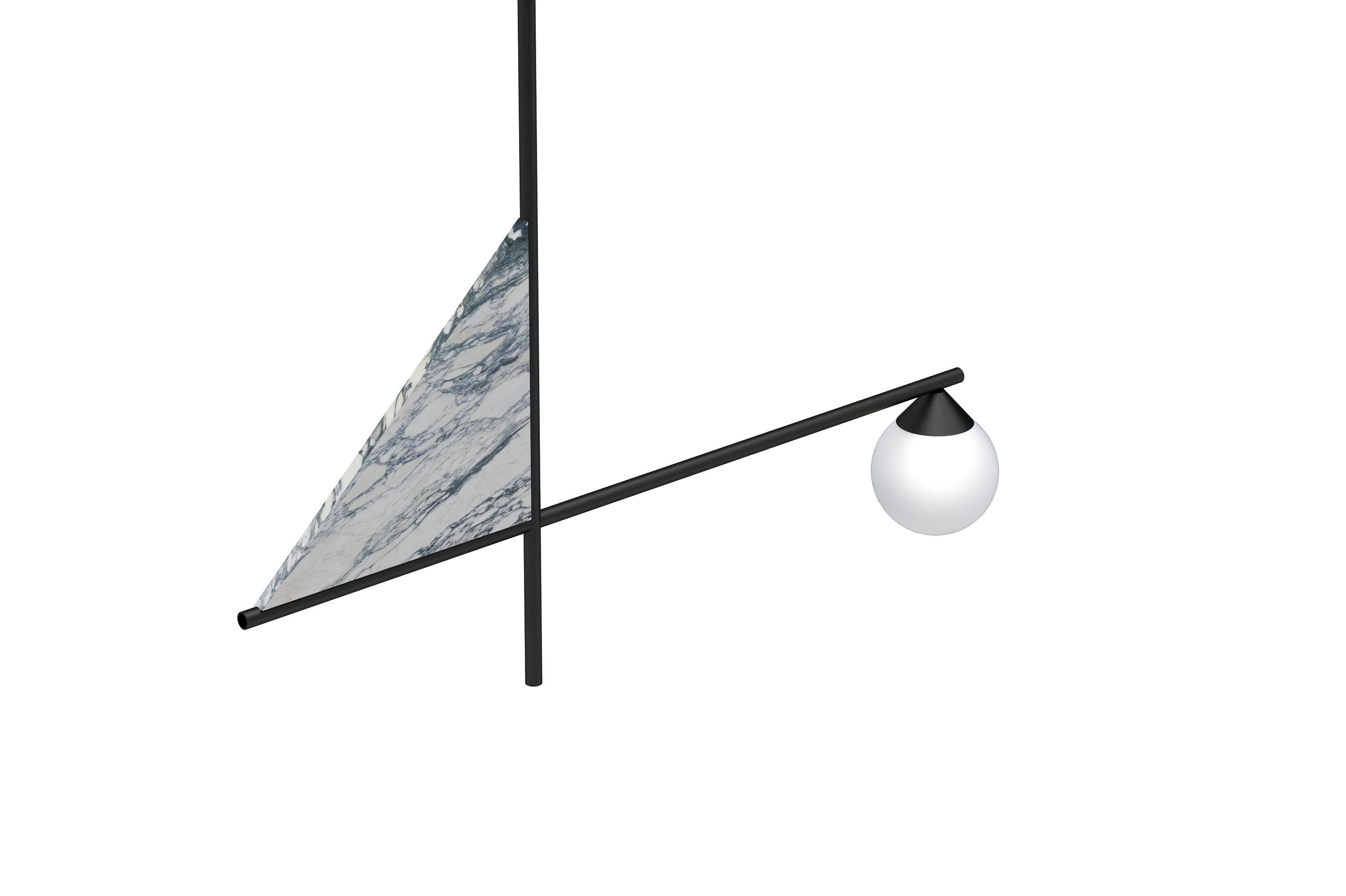 This lighting feature is made of white Carrara marble with green veins. Originating from Italy, this triangular shaped sits on two perpendicular black metal poles. One bulb hangs from the end of the horizontal pole. The shape of this light is