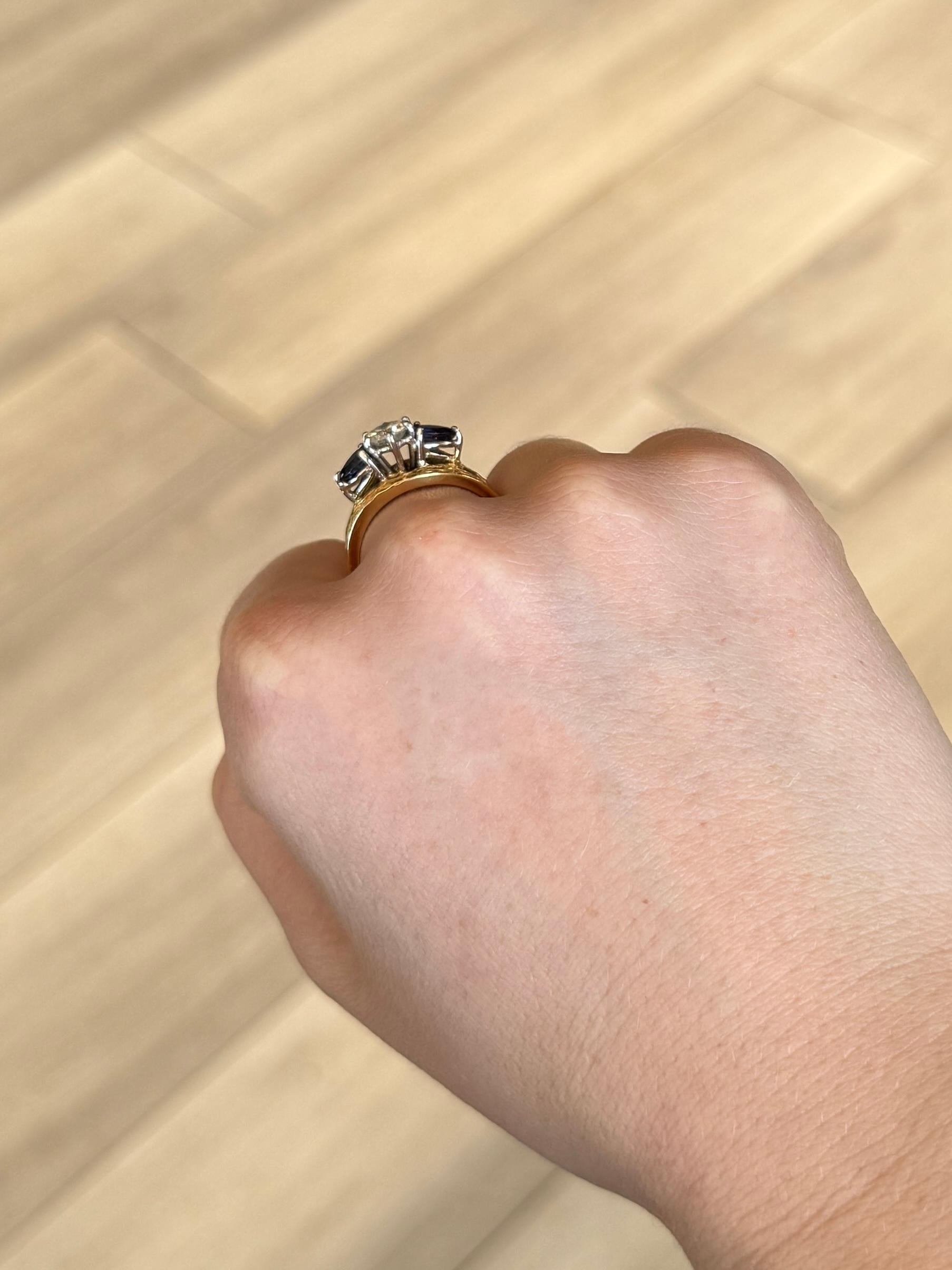 Dieser atemberaubende Ring aus 18 Karat Gold und Platin trägt einen Diamanten in der Mitte und funkelnde blaue, birnenförmige Saphire an beiden Seiten. Der Diamant misst 75 Pence und die Saphire je 30 Pence. Die Steine sind in Platin gefasst.