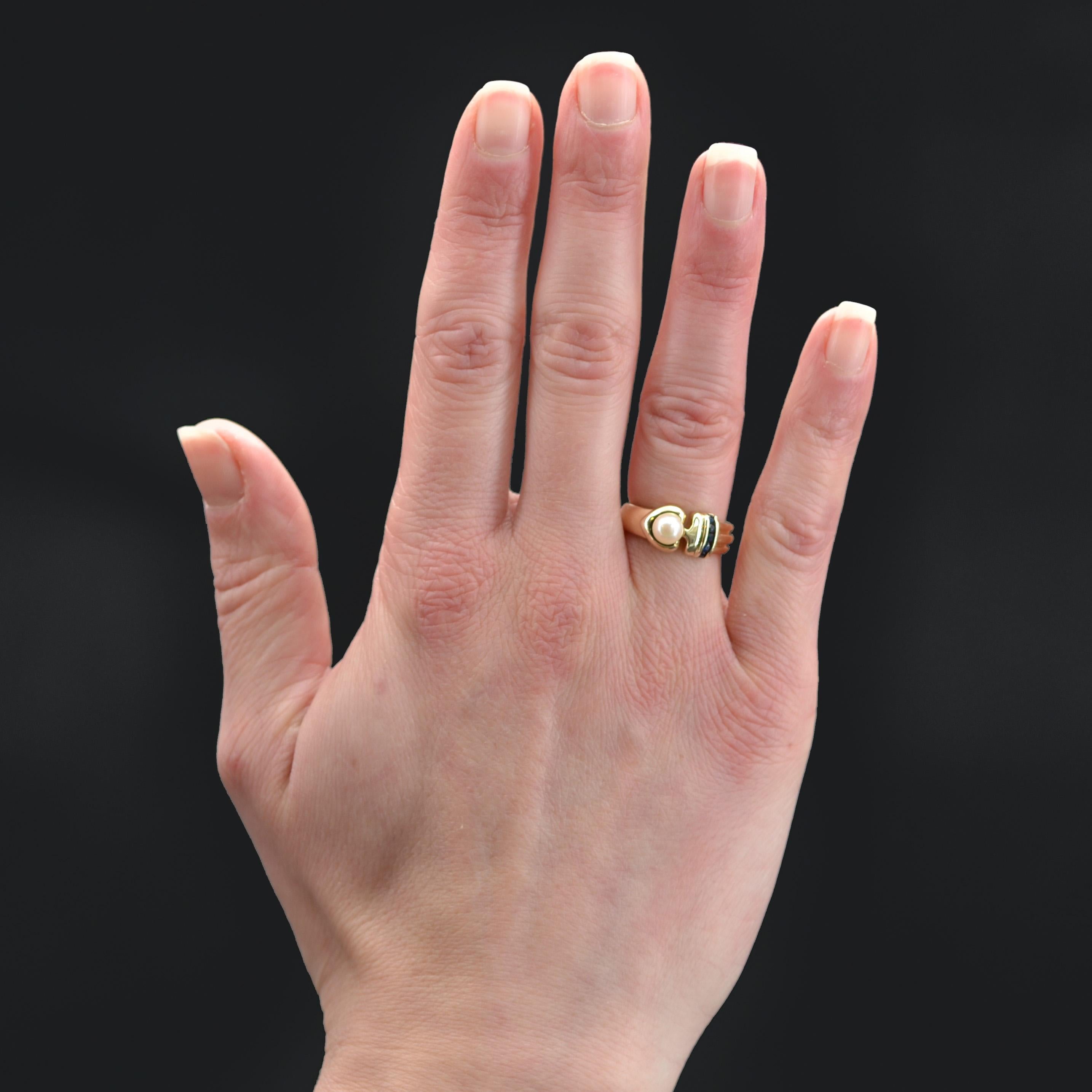 Ring in 14 karat yellow gold.
Modern ring in yellow gold, it represents an ace of spades whose heart is set with a cultured pearl and the base of round sapphires in rail setting. The ring is chiseled from one side to the base giving an effect of