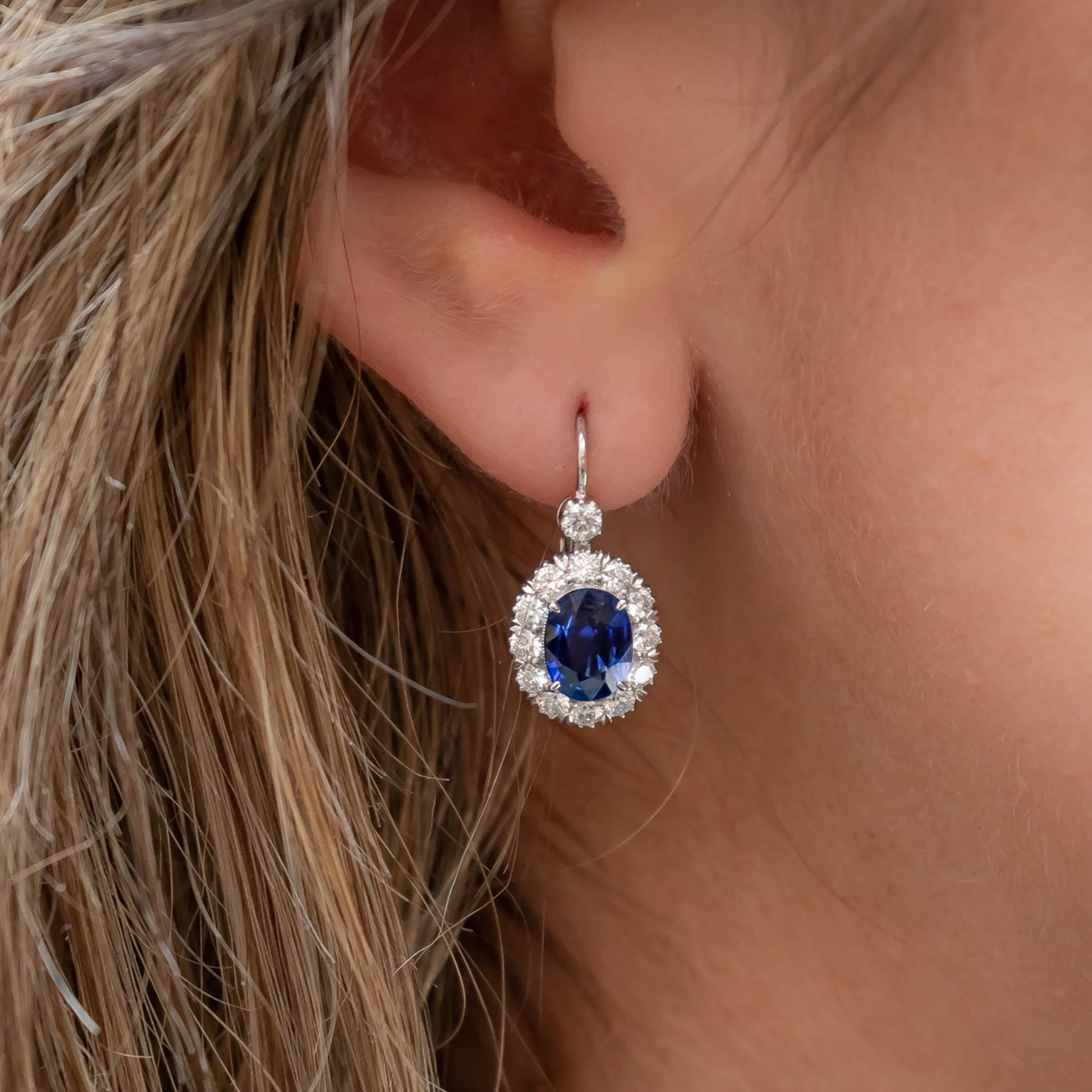 A pair of sapphire, diamond and platinum cluster drop earrings, set with central, oval, faceted sapphires, with a total weight of 2.52 carats, with surrounding round brilliant-cut diamonds, suspended from a single round brilliant cut diamond, with