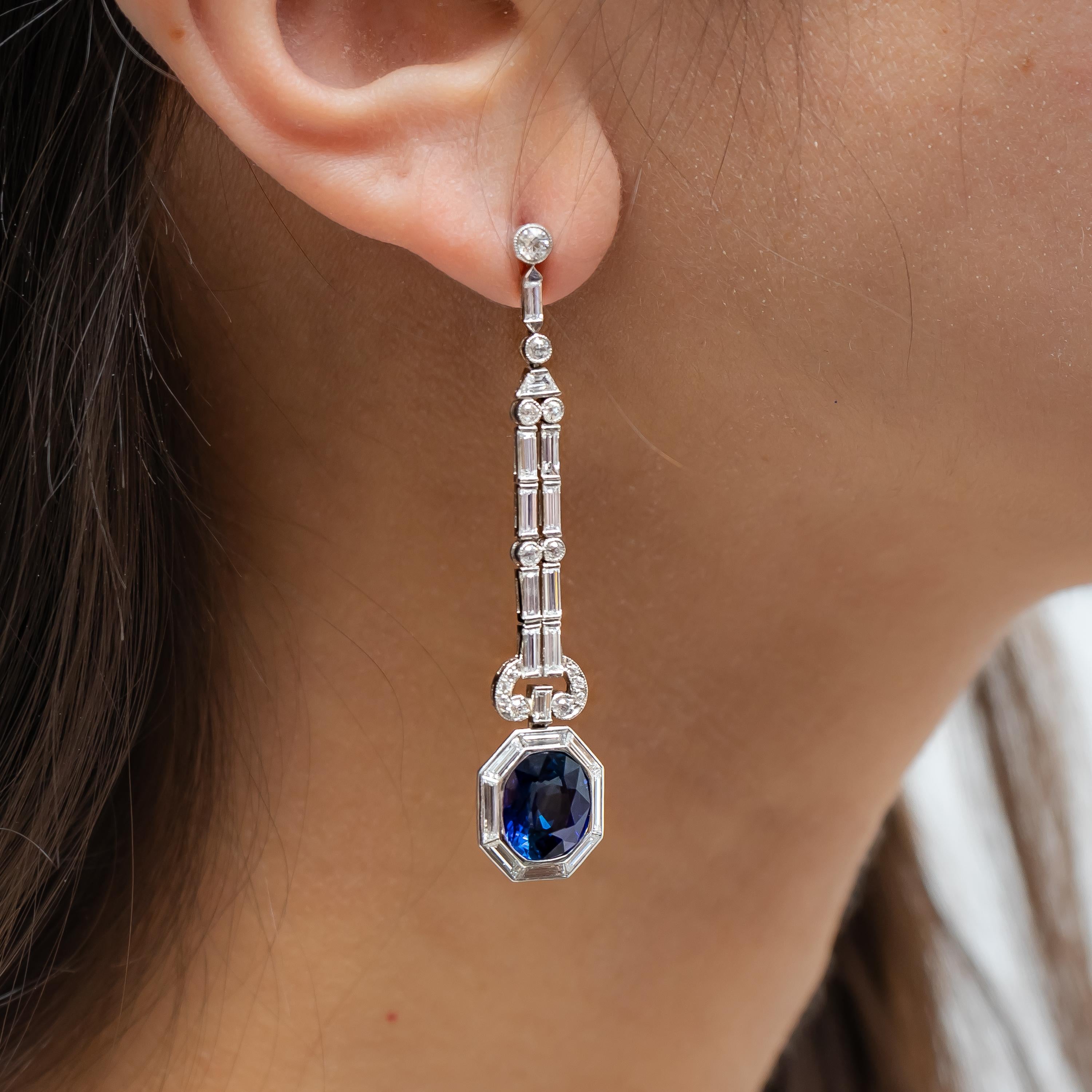 A pair of modern sapphire and diamond drop earrings, the top studs are set with old cut diamonds, with baguette-cut diamonds below and old-cut diamonds, above trapezoid diamonds, below this is a pendant of pairs of old-cut and baguette-cut diamonds,