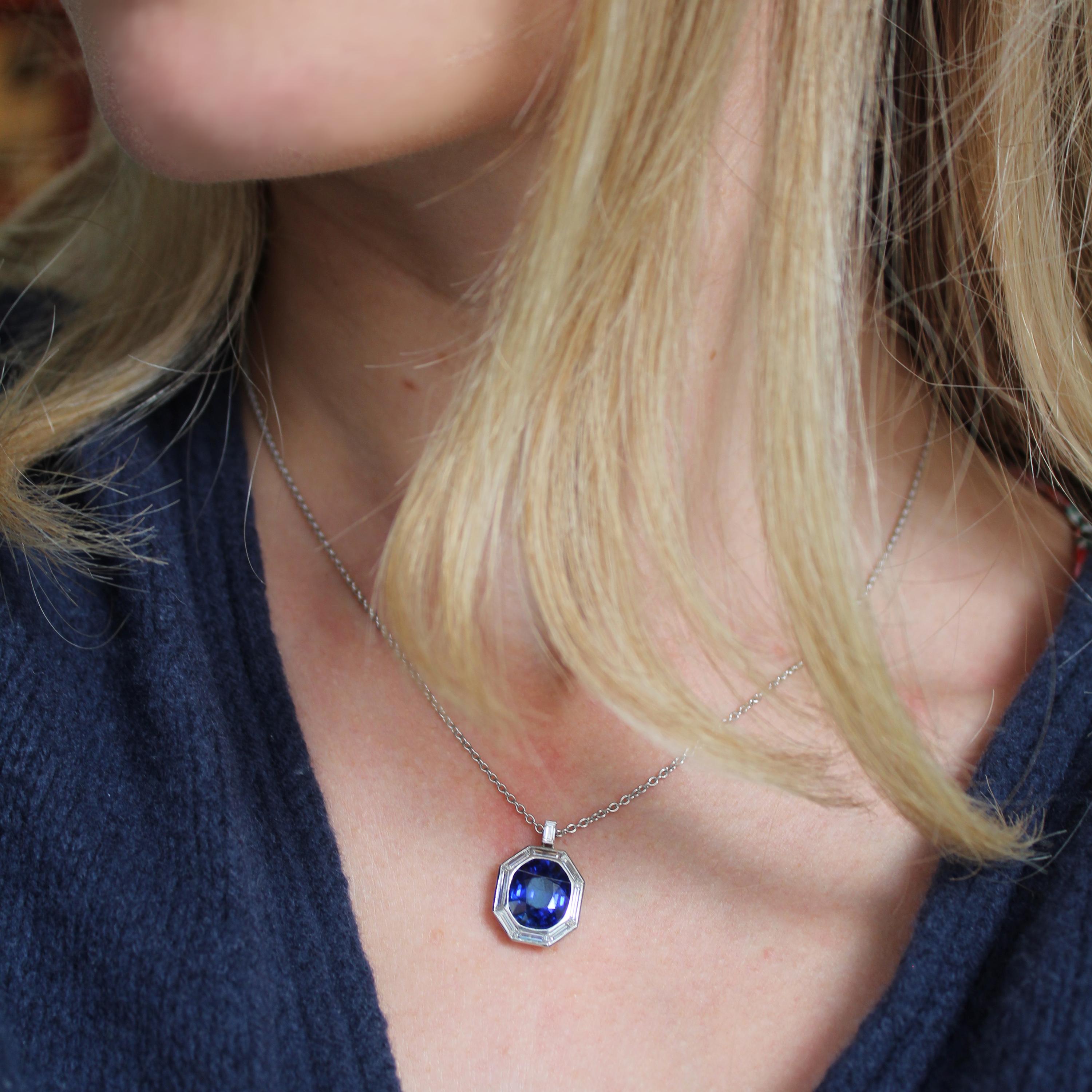 A modern sapphire and diamond pendant, set with an oval faceted sapphire, with a mitre set surround, with trapezoid baguette-cut diamonds, in rub over settings, over a basket at the back, the bail is set with a baguette-cut diamond and the chain