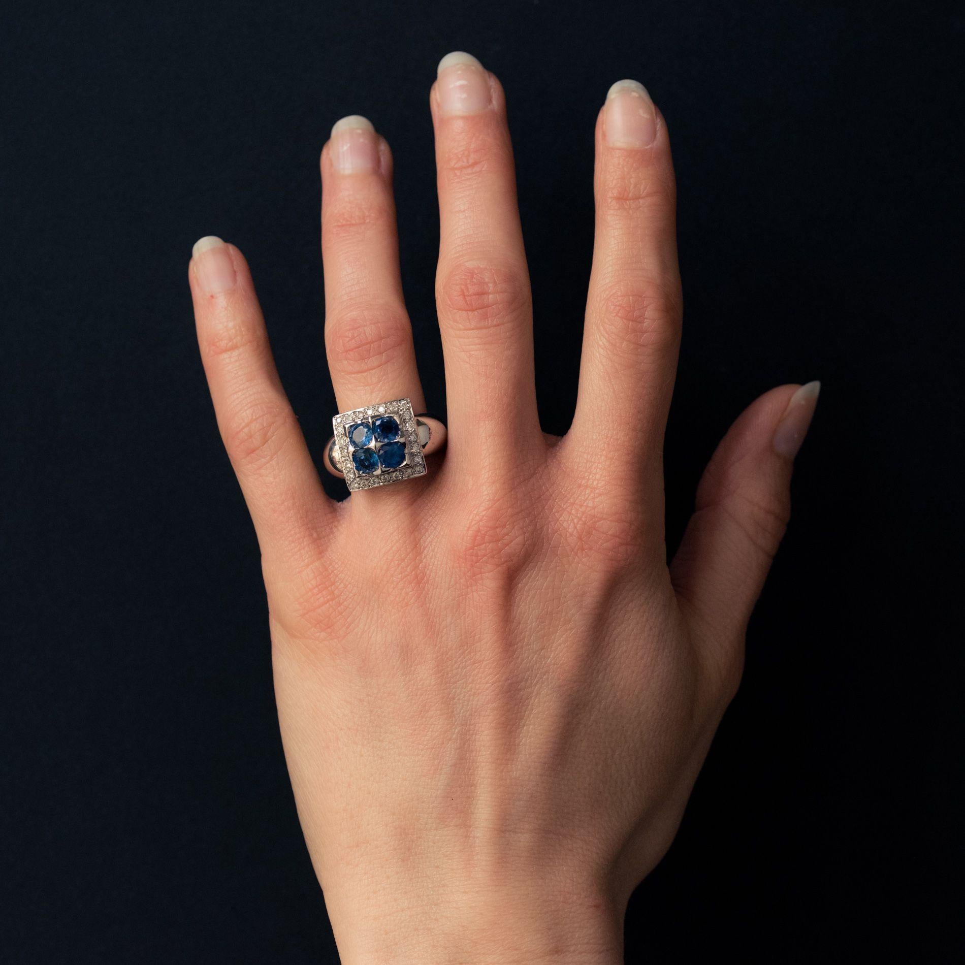 Ring in 18 karat white gold. 
In the form of a square, this voluminous sapphire and white gold ring is set with 4 round blue sapphires with a border of brilliant cut diamonds. The beginning of the ring band on each side is large and rounded. 
Total