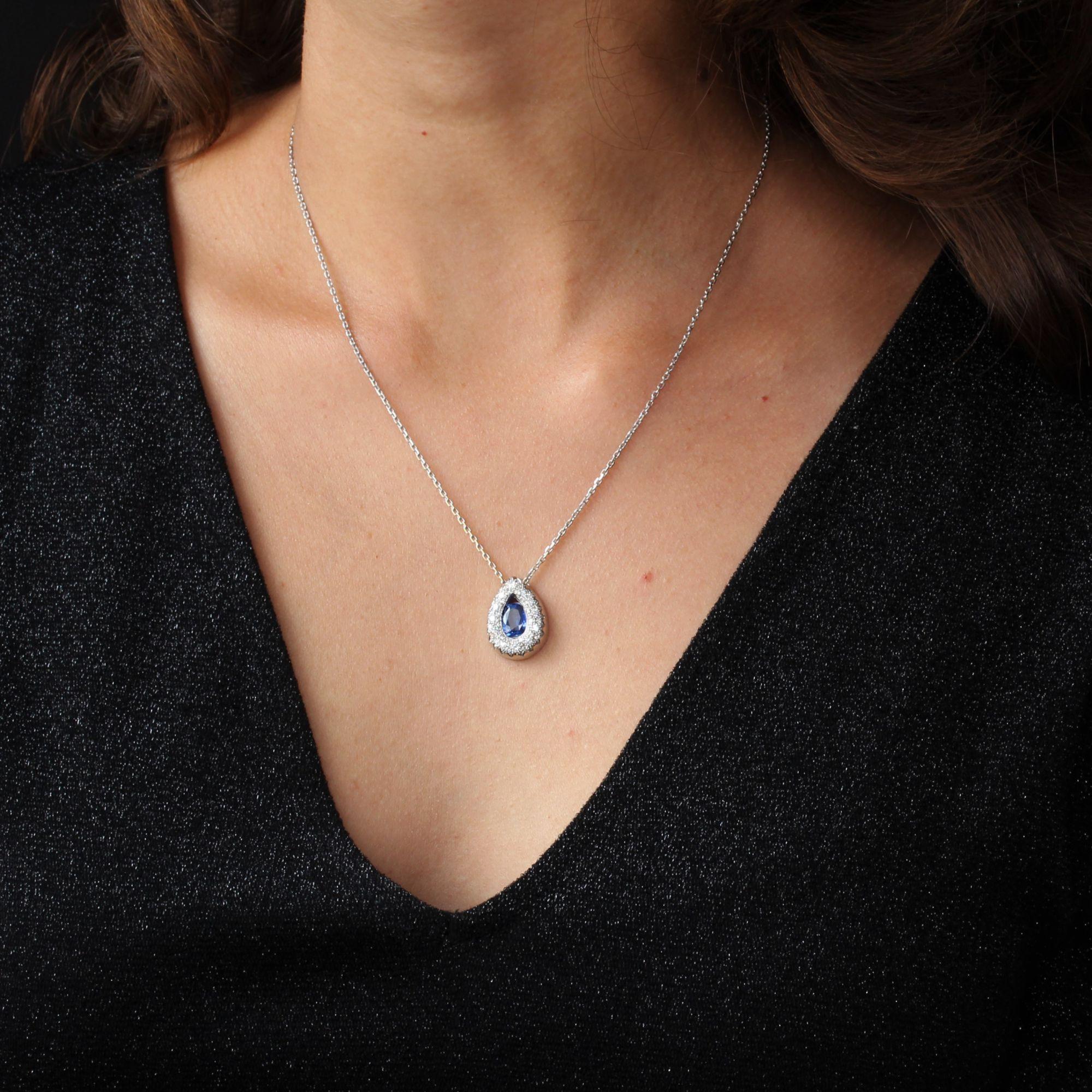 Pendant in 18 karat white gold, eagle head hallmark.
In the shape of a drop, this jewelry pendant has in the center a blue cushion sapphire surrounded by a pavement of diamonds. The chain is a thin convict mesh filed. The clasp is a spring