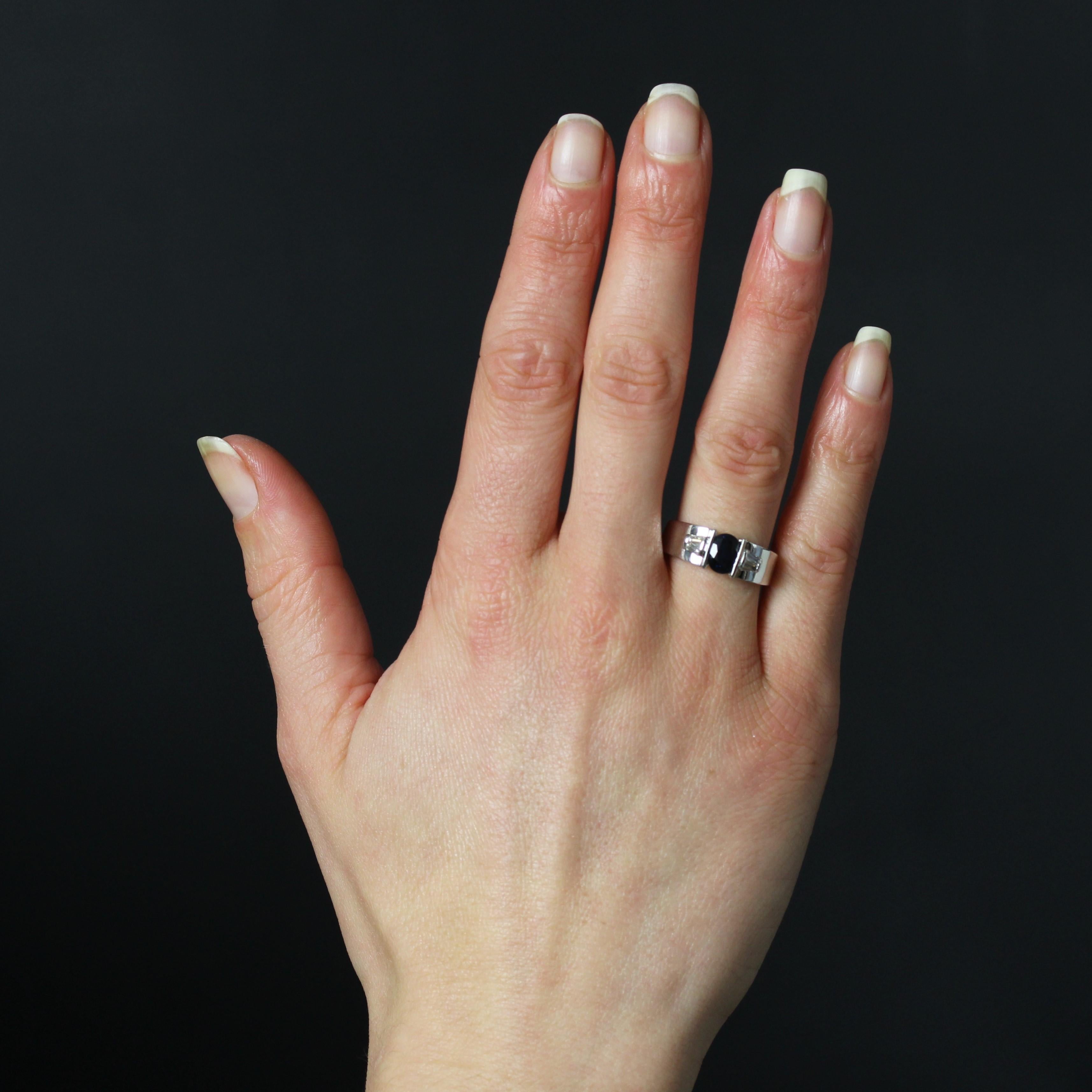 Anello in oro bianco 18 carati, marchio di fabbrica con testa d'aquila.
Questo anello contemporaneo presenta una fascia larga e piatta con uno zaffiro ovale incastonato sulla parte superiore. Su entrambi i lati della fascia sono incastonati 2x2