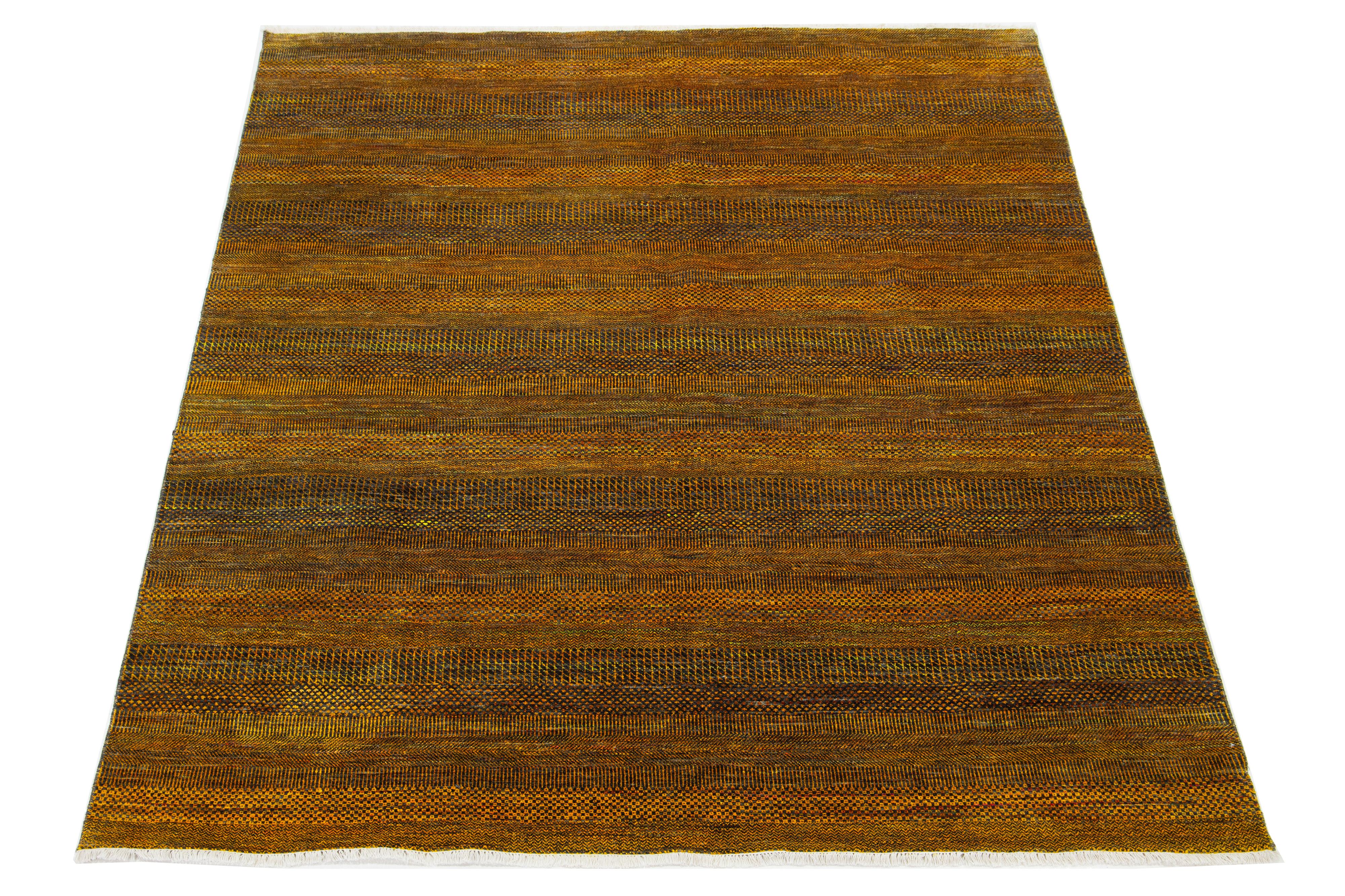Dieser elegante, handgeknüpfte Wollteppich zeichnet sich durch ein modernes Design aus. Es zeigt ein sorgfältig gearbeitetes Feld in Goldrute-, Rost-, Grau- und Grüntönen, das mit verschlungenen geometrischen Mustern verziert ist.

Dieser Teppich