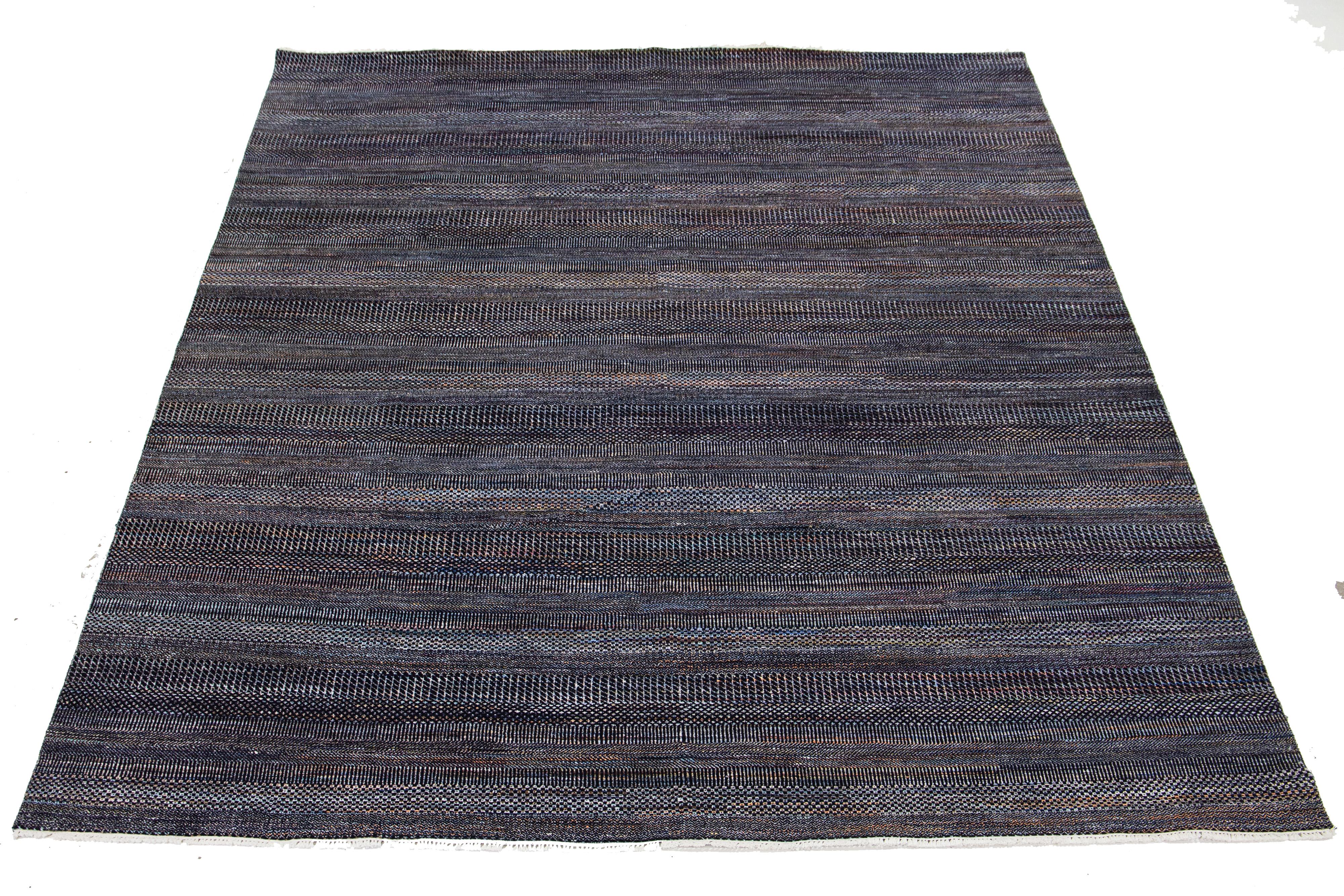 Questo tappeto in lana annodato a mano presenta un design moderno con un'accurata miscela di toni ruggine, grigio e blu, accentuati da dettagliati motivi geometrici che catturano lo sguardo.

Questo tappeto misura 9'2