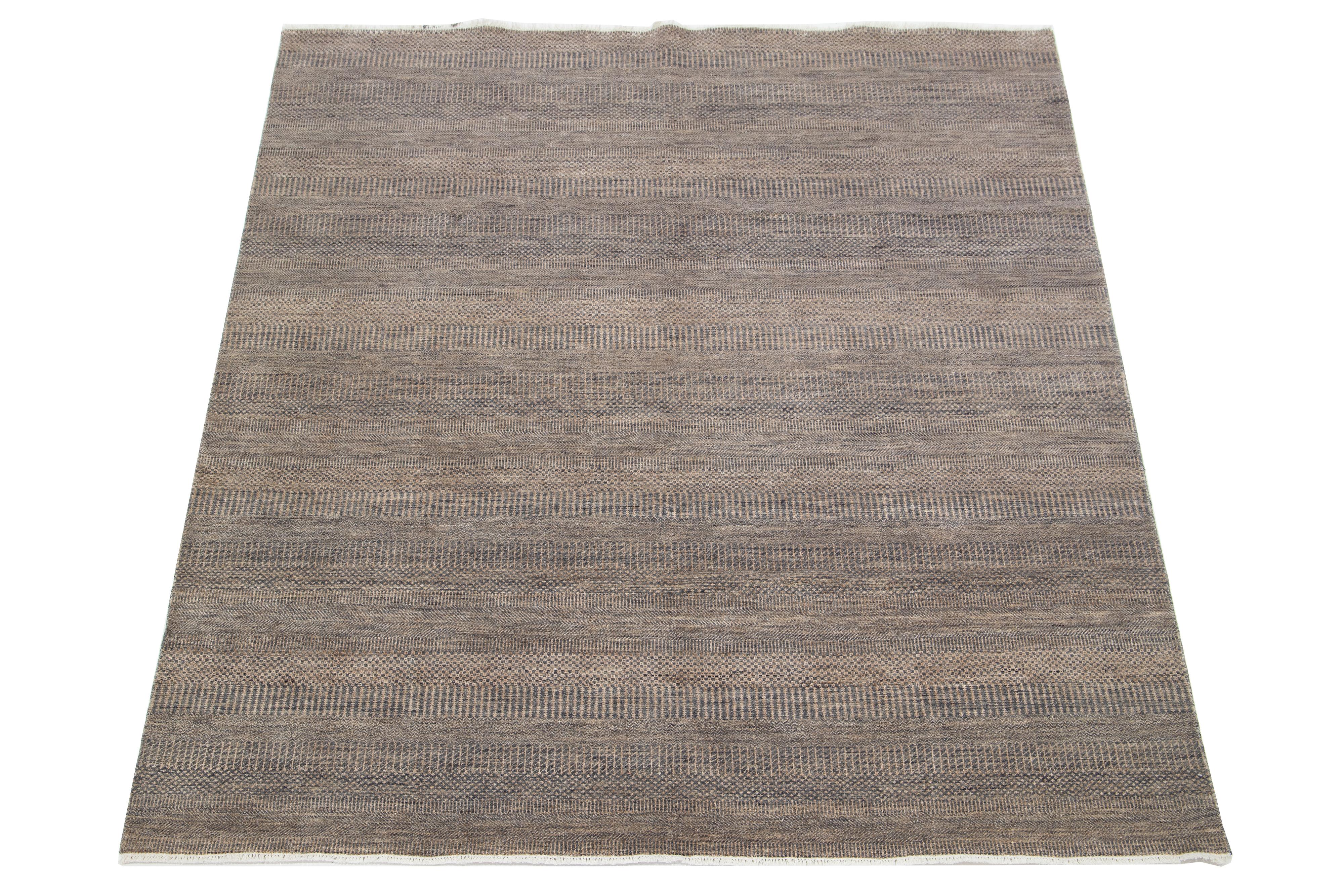 Dieser elegante, handgeknüpfte Wollteppich zeichnet sich durch ein modernes Design aus. Es zeigt ein sorgfältig gearbeitetes Feld in Braun, das mit komplizierten geometrischen Mustern verziert ist.

Dieser Teppich misst 8'1