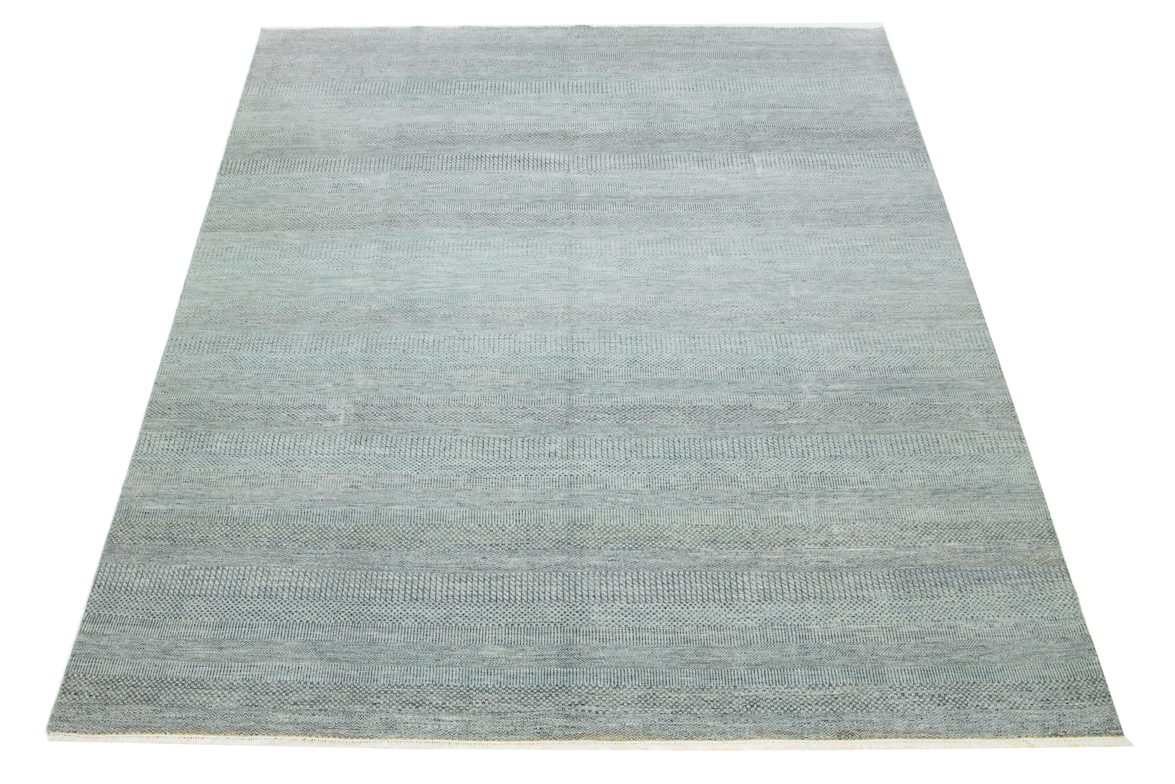 Dieser elegante, handgeknüpfte Wollteppich zeichnet sich durch ein modernes Design aus. Es zeigt ein sorgfältig gearbeitetes Feld in Hellgrün, das mit verschlungenen geometrischen Mustern verziert ist.

Dieser Teppich misst 9'1