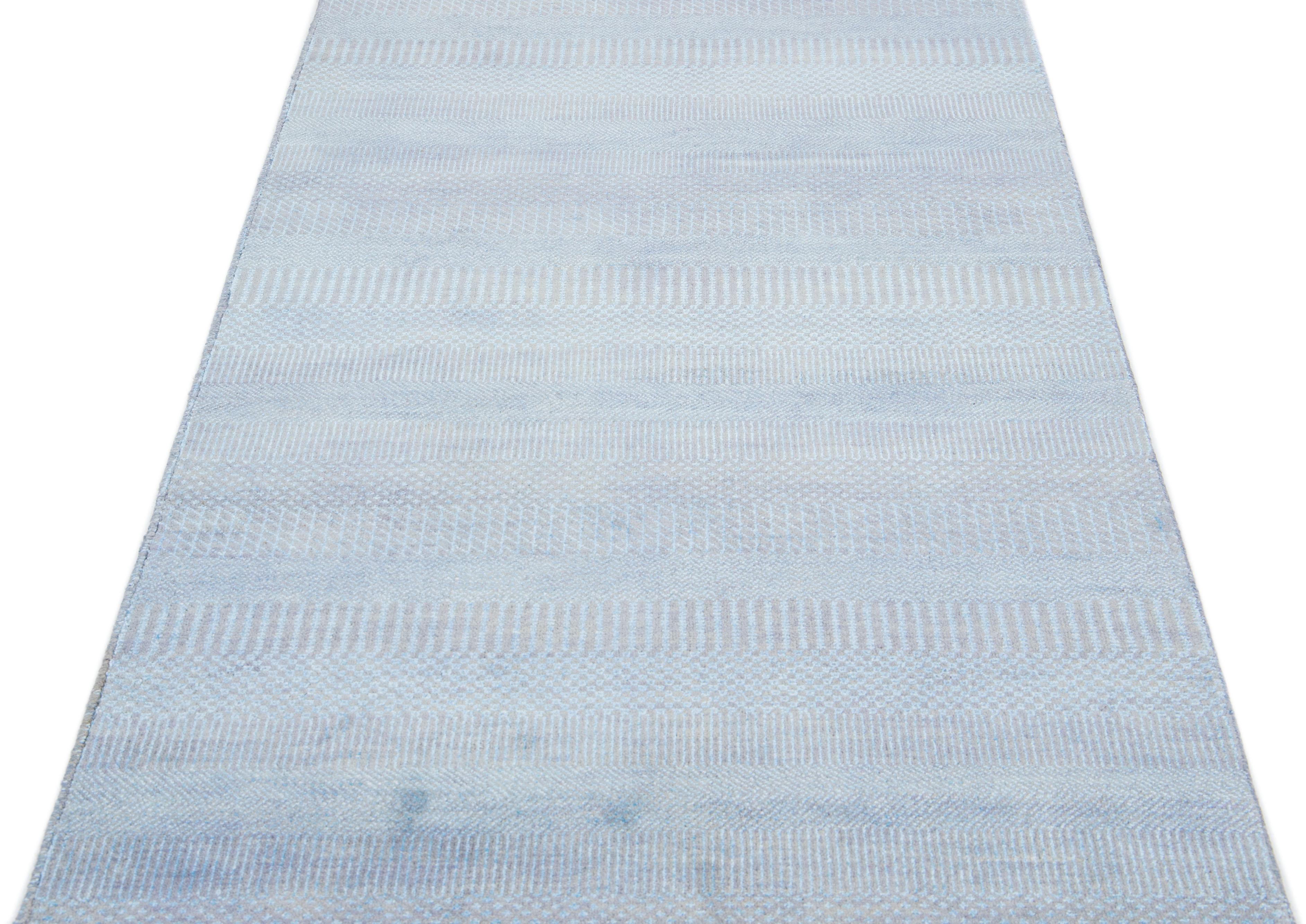 This long hand-knotted rug is made of wool. It features a subtle light blue color scheme accented by an all-over geometric pattern—an ideal addition to any contemporary interior.

This rug measures 3'5
