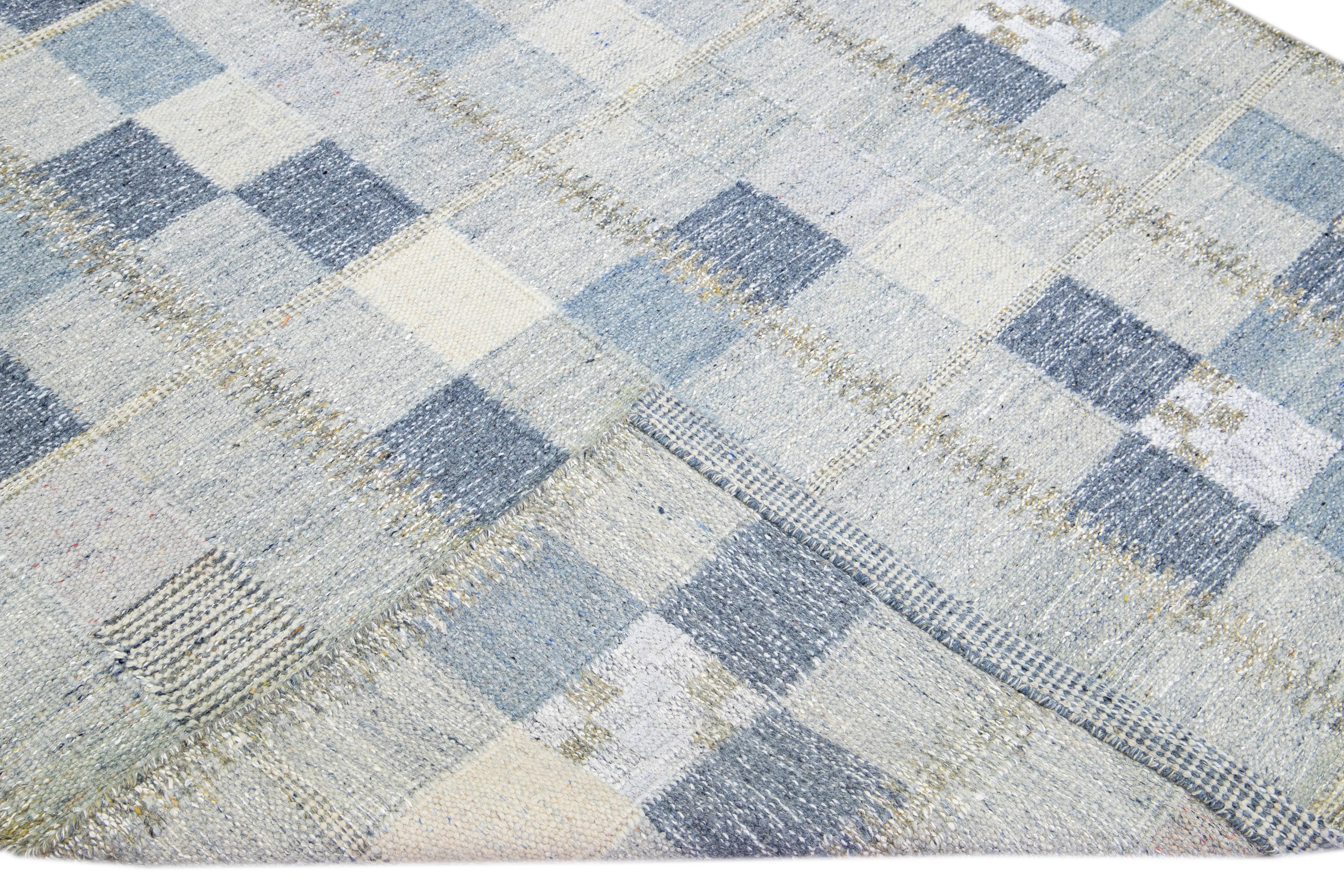 Magnifique tapis en laine de style scandinave avec un champ bleu et gris. Ce tapis moderne présente des accents de blanc et de jaune dans un magnifique motif géométrique.

 Ce tapis mesure : 6'1