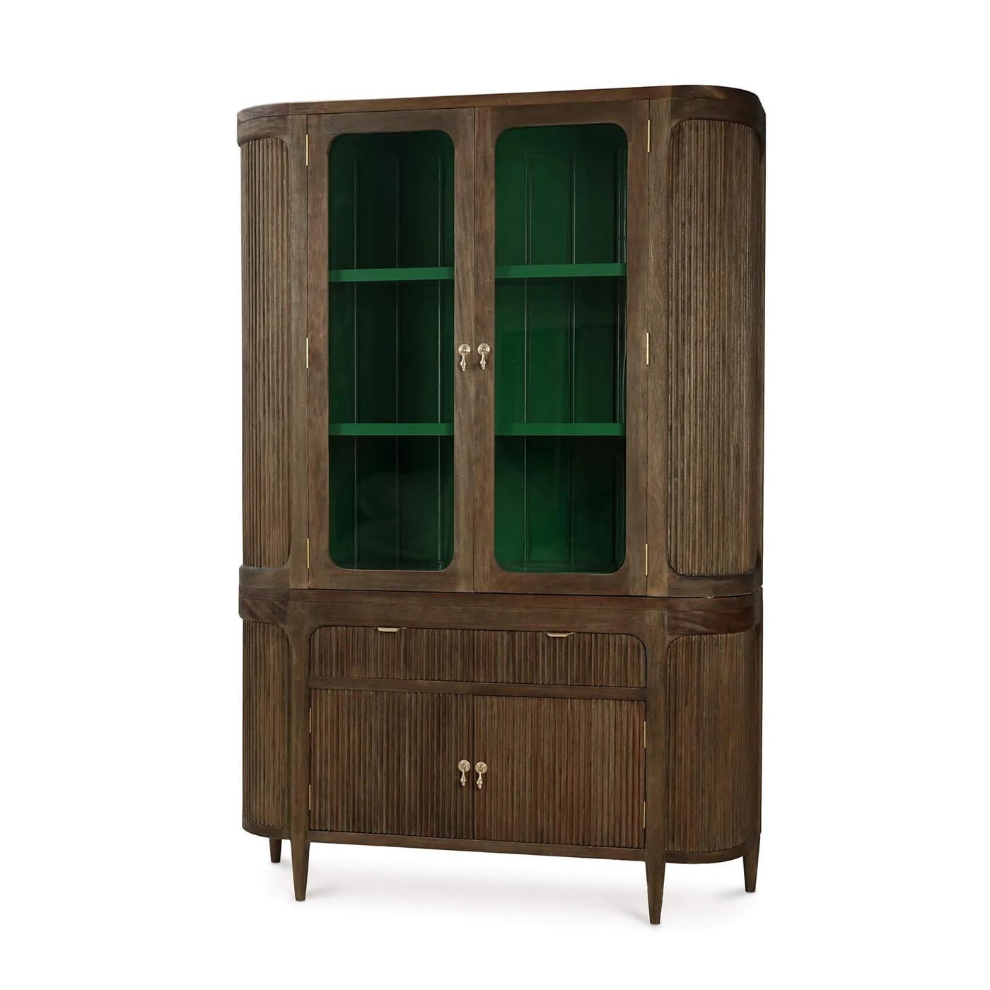 Crafted with a demilune silhouette, its curved form is finished in a rich Rugged Tea stain that highlights the natural grain of the wood. Behind glass doors, a Jade Green painted interior adds a vibrant counterpoint, offering a dramatic stage for