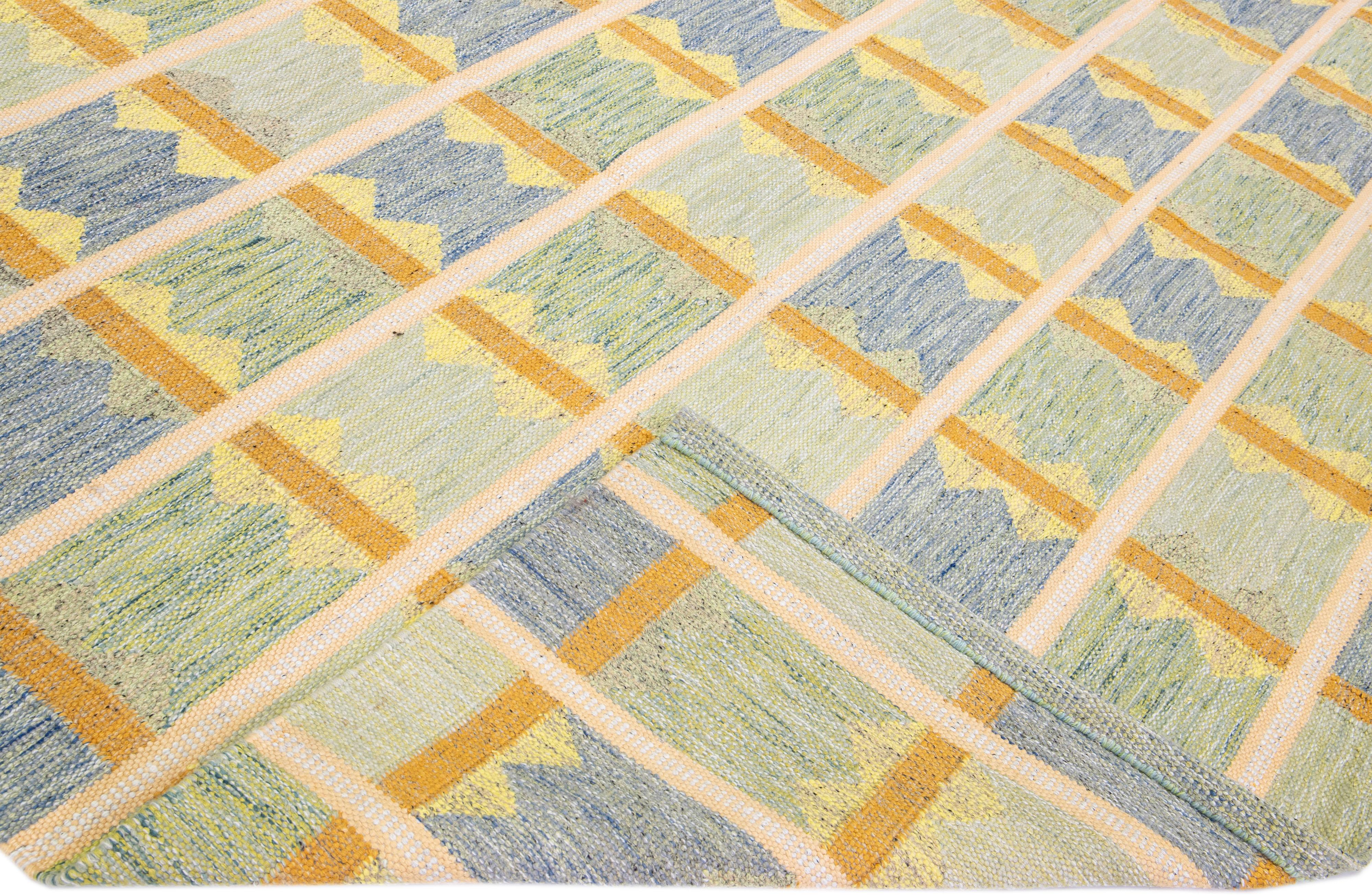 Magnifique tapis en laine de style scandinave avec un champ vert. Ce tapis moderne présente des accents de jaune, de bleu et d'orange dans un magnifique motif géométrique.

 Ce tapis mesure : 12'2
