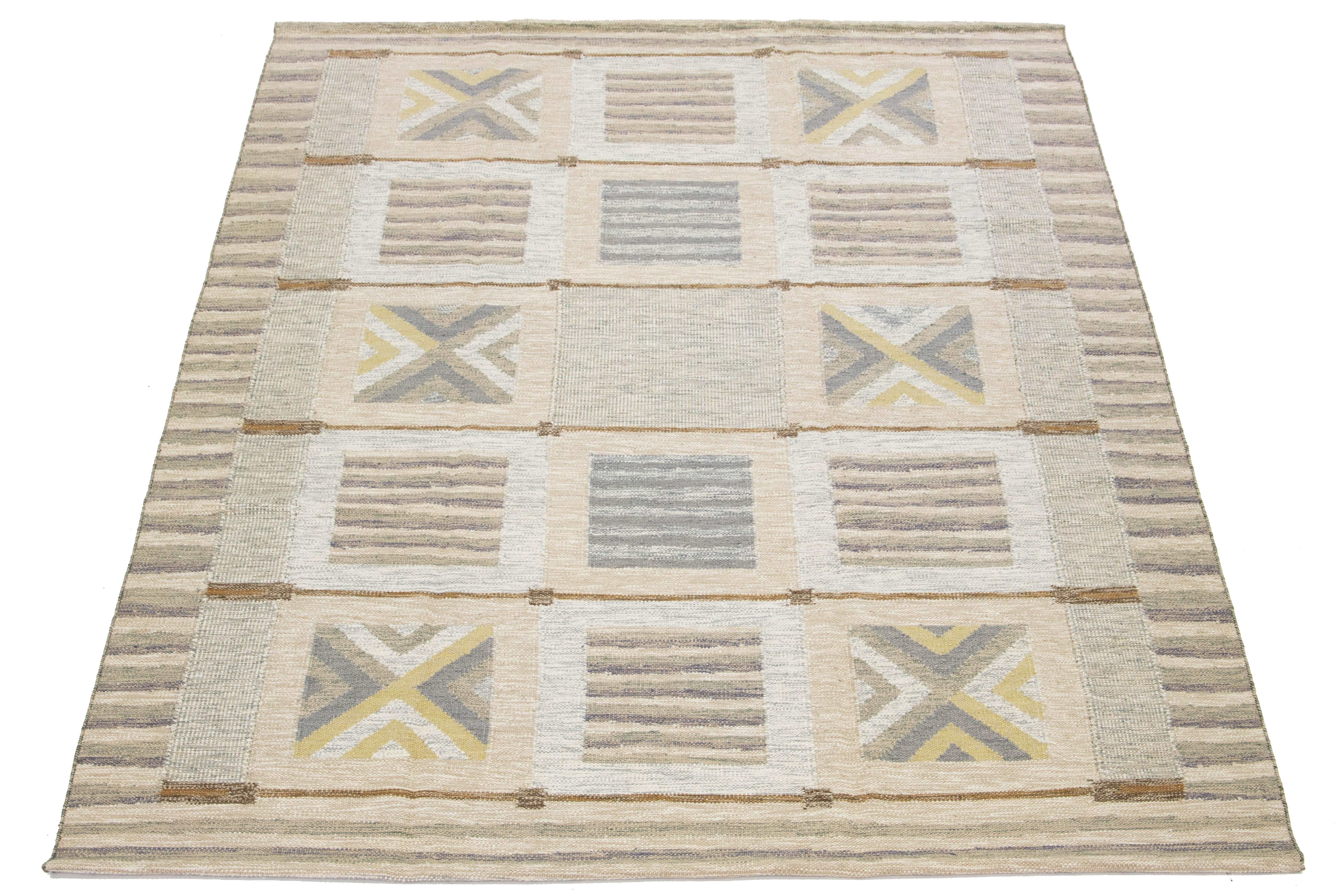 Découvrez le charme de ce magnifique tapis de style suédois, noué à la main de manière experte à partir de laine de première qualité. Son élégante palette de couleurs associe avec art des tons de beige, de gris et de marron, tandis que des touches