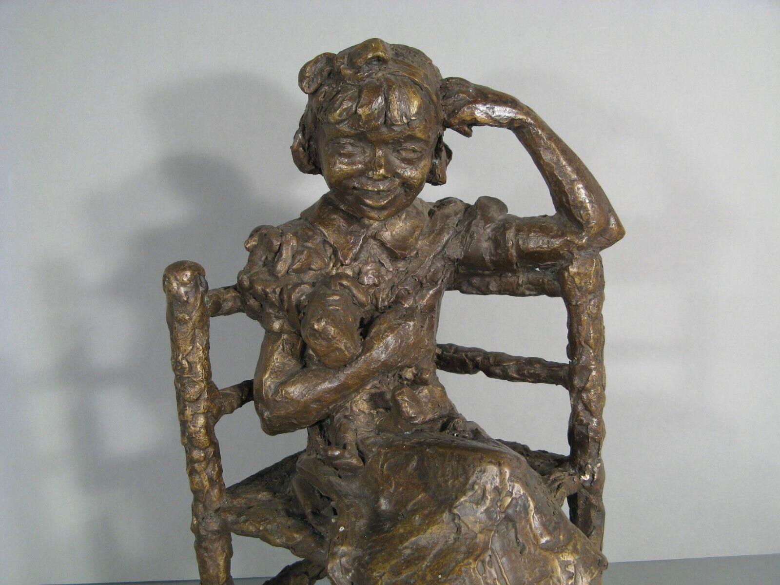 This charming bronze sculpture, created in the modern style, depicts a young girl seated and holding a fox terrier dog (or a toy resembling one) between her arms. The piece is finished with a rich brown patina, enhancing its warm and timeless