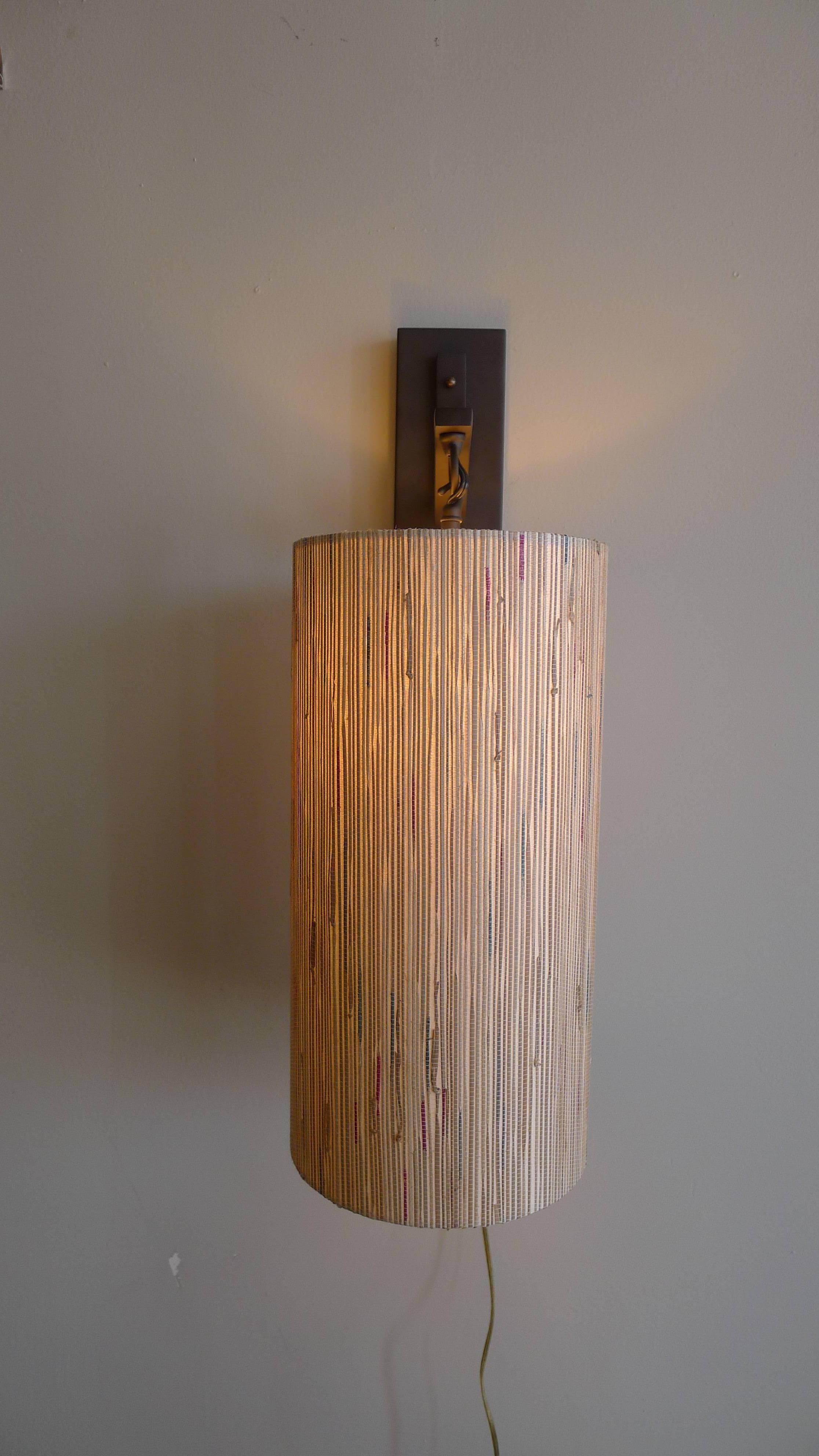 Modern sconce in oil rubbed bronze metal with custom grass cloth shade by Paul Marra. Currently a pair available, or by order. The custom shade is made of grasscloth in subtle colors. Price is per each sconce. Shade 16 x 8