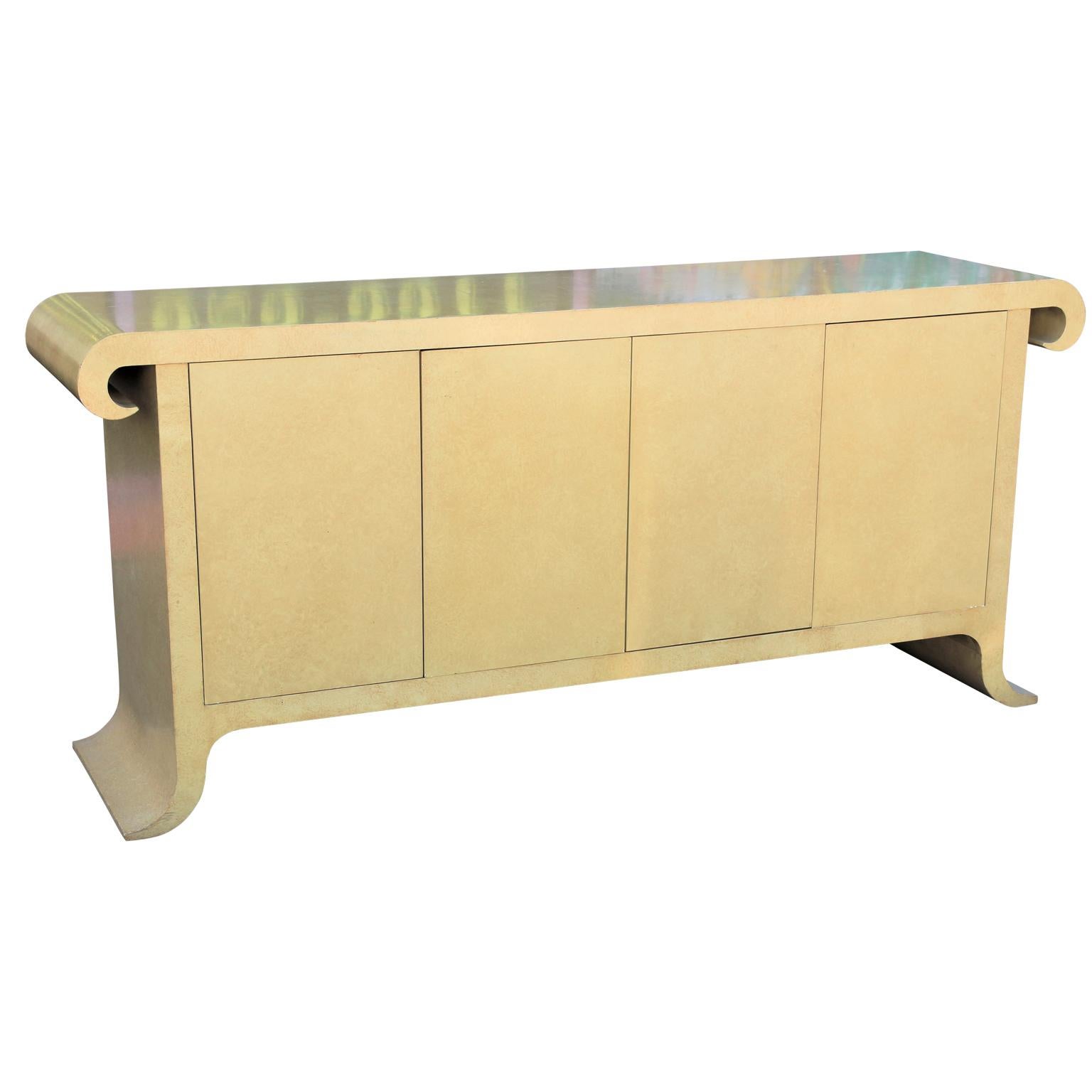 Modern cream colored scroll top sideboard or credenza designed by Alessandro Gambrielli for Baker Furniture in the style of Karl Springer. The case features two pull out drawers on the left and an adjustable shelf on the right.