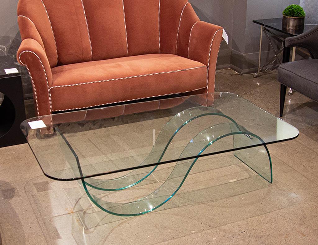 Modern sculpted curved glass coffee table. Unique curved modern design all constructed and moulded from glass. American, circa 1980s, all original. Glass top has rounded corner details. In great condition, top glass has minor scratching consistent