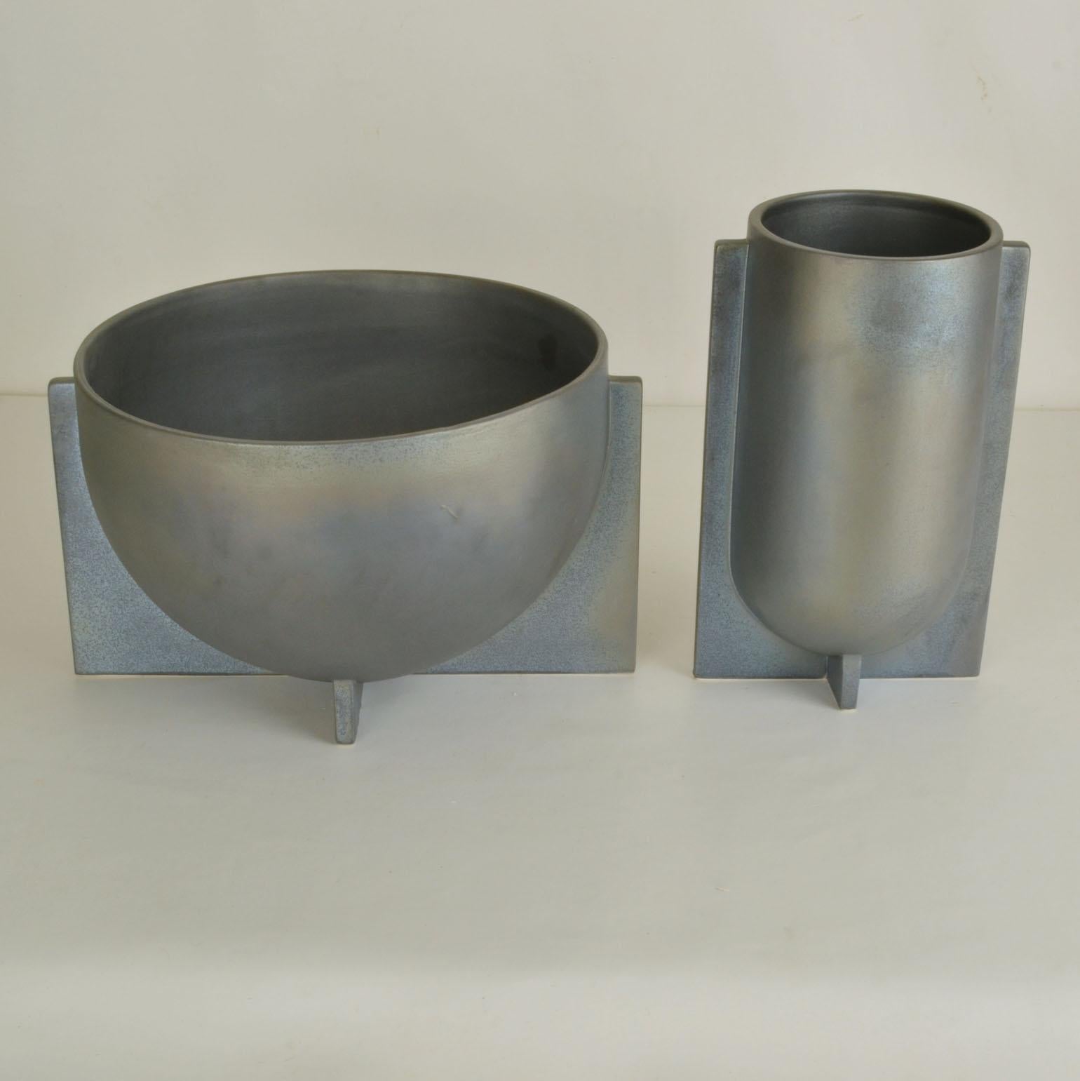 Pair of decorative sculptural vases with soft metal blue-grey glaze in different sizes have a modern geometric shape. They will perfectly stage flowers or plants. In unused condition.

Individual sizes; 
Width tall one 13 x 16, Height 26 cm 
Width