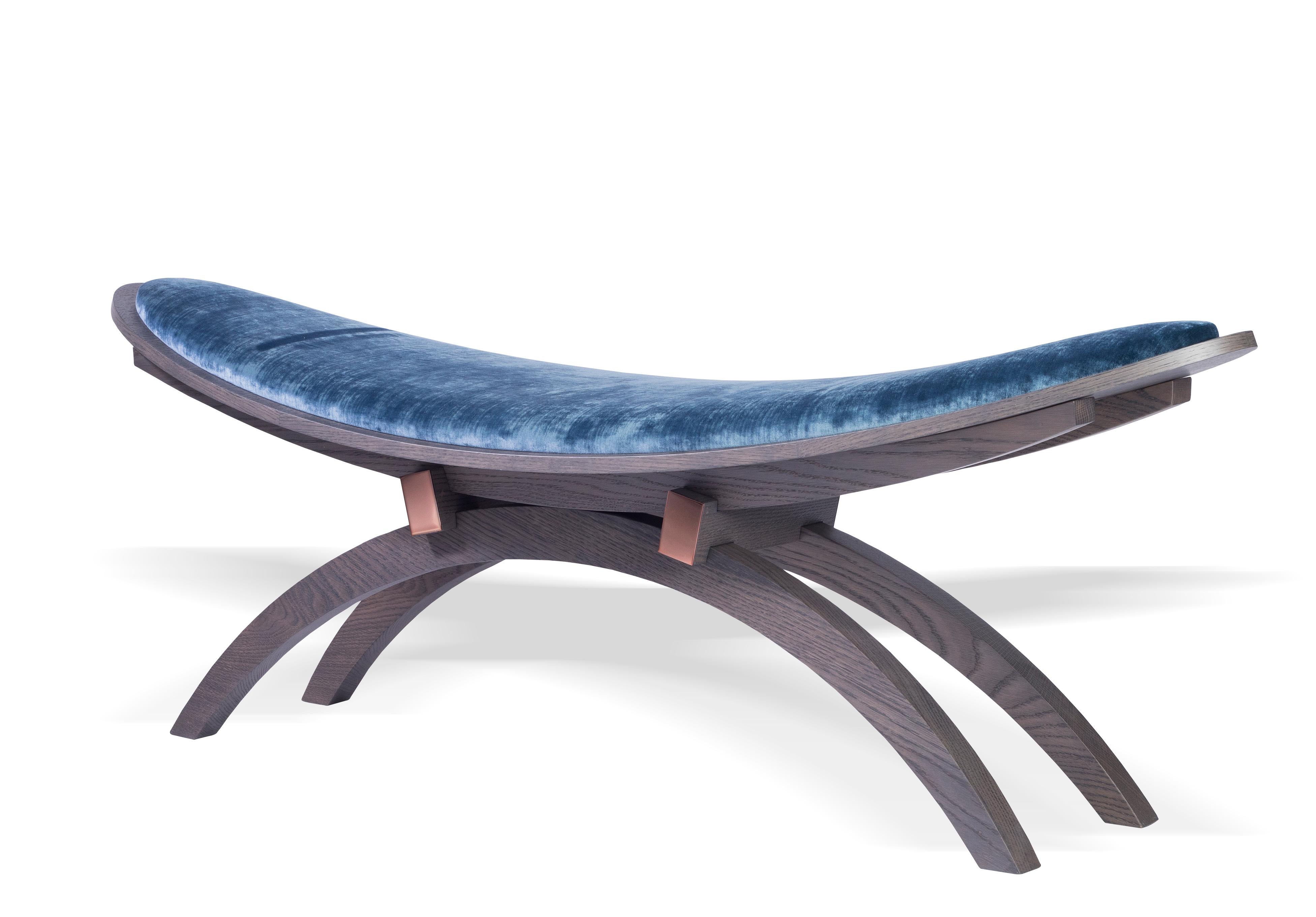 A sculptural, elliptical bench inspired by the lucky charm of a dragonfly. The elliptical-shaped upholstered wood shell in combination with the diligently crafted wood base composes this sculptural bench. The noble metal plates give an additional