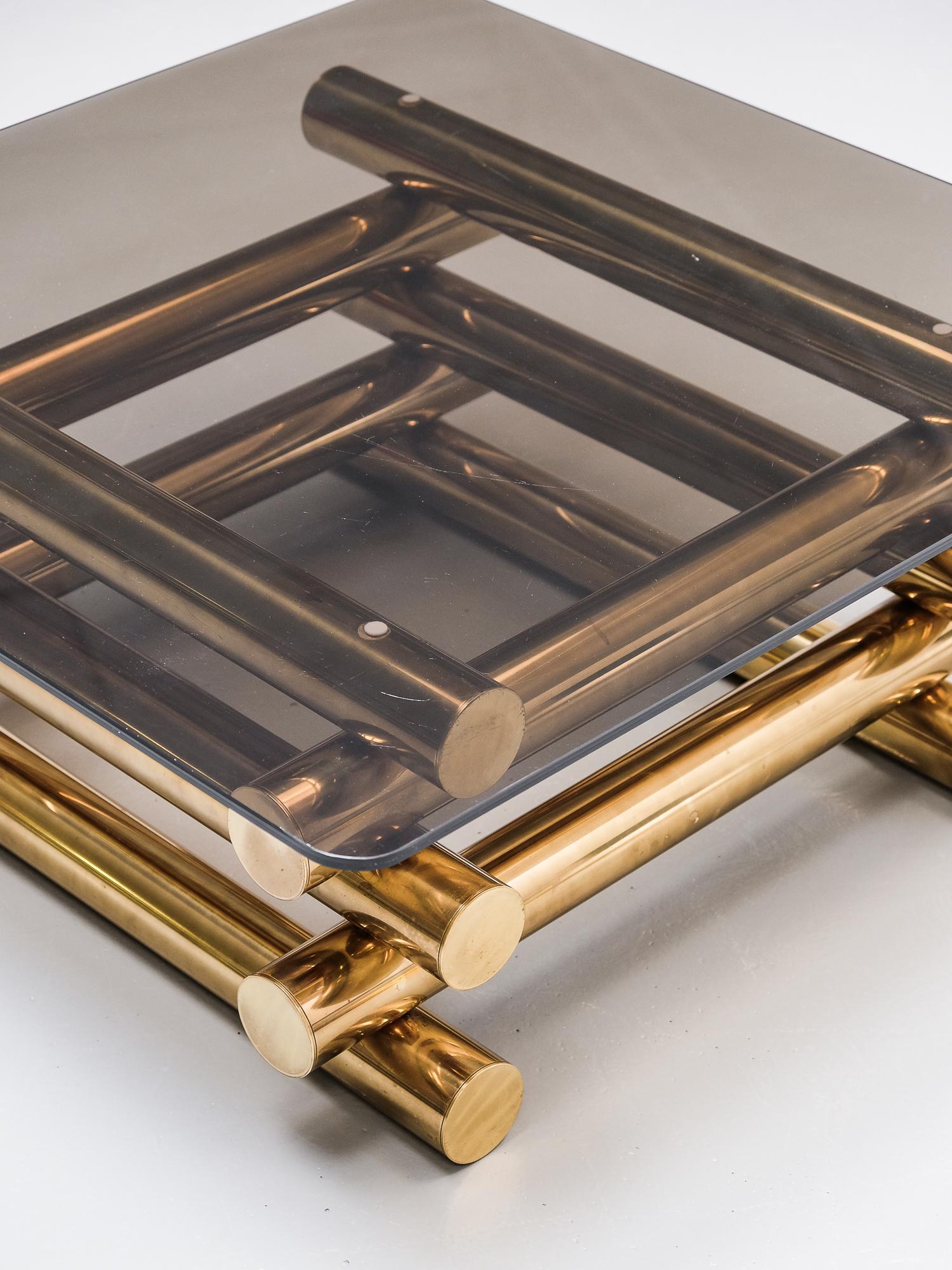 A great 1970s design coffee table. It features a stacked brass base with thick smoked glass top.