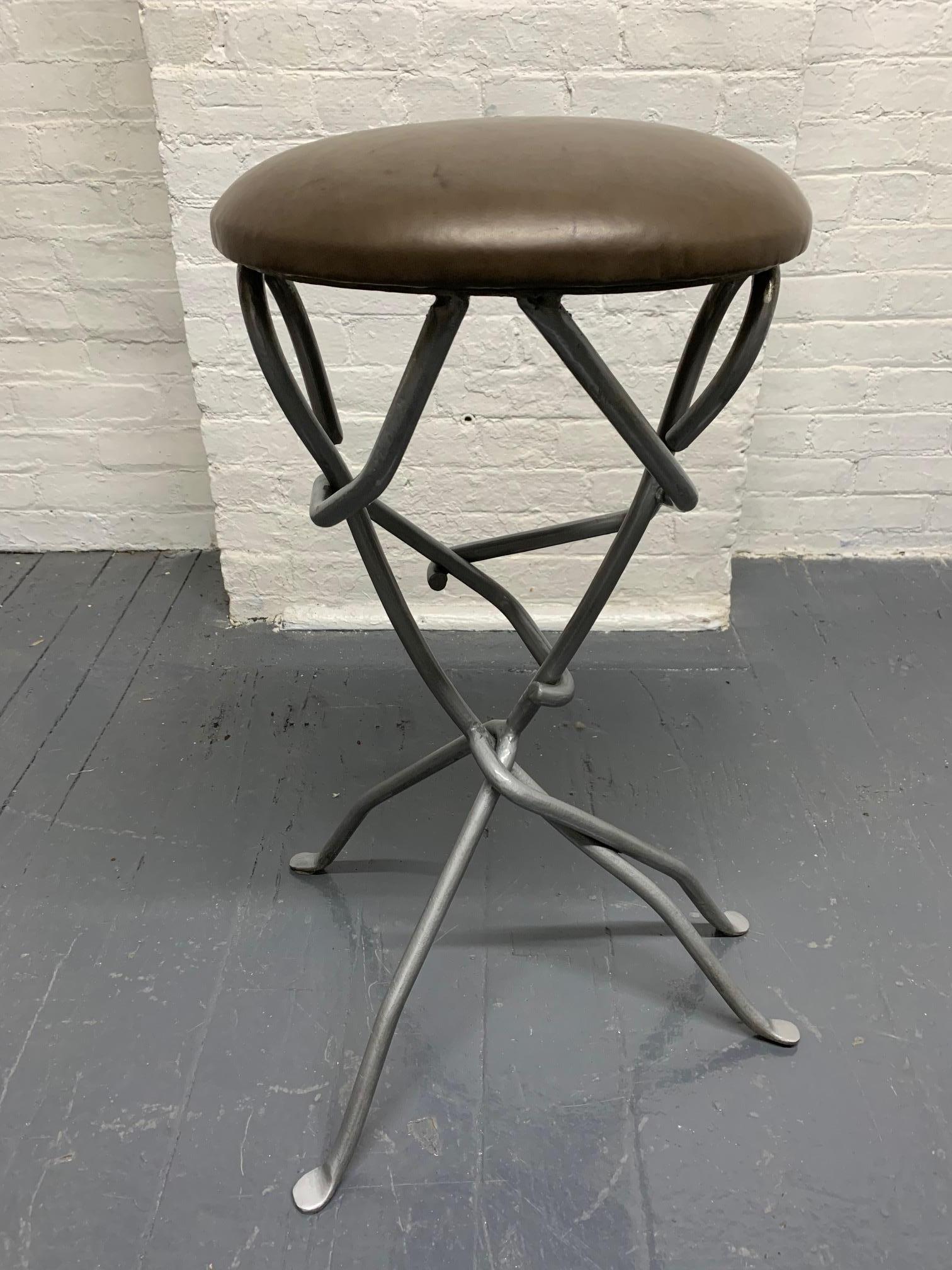 Modern sculptural wrought iron stool with leather seat. The frame is two individuals hugging each other. 
 