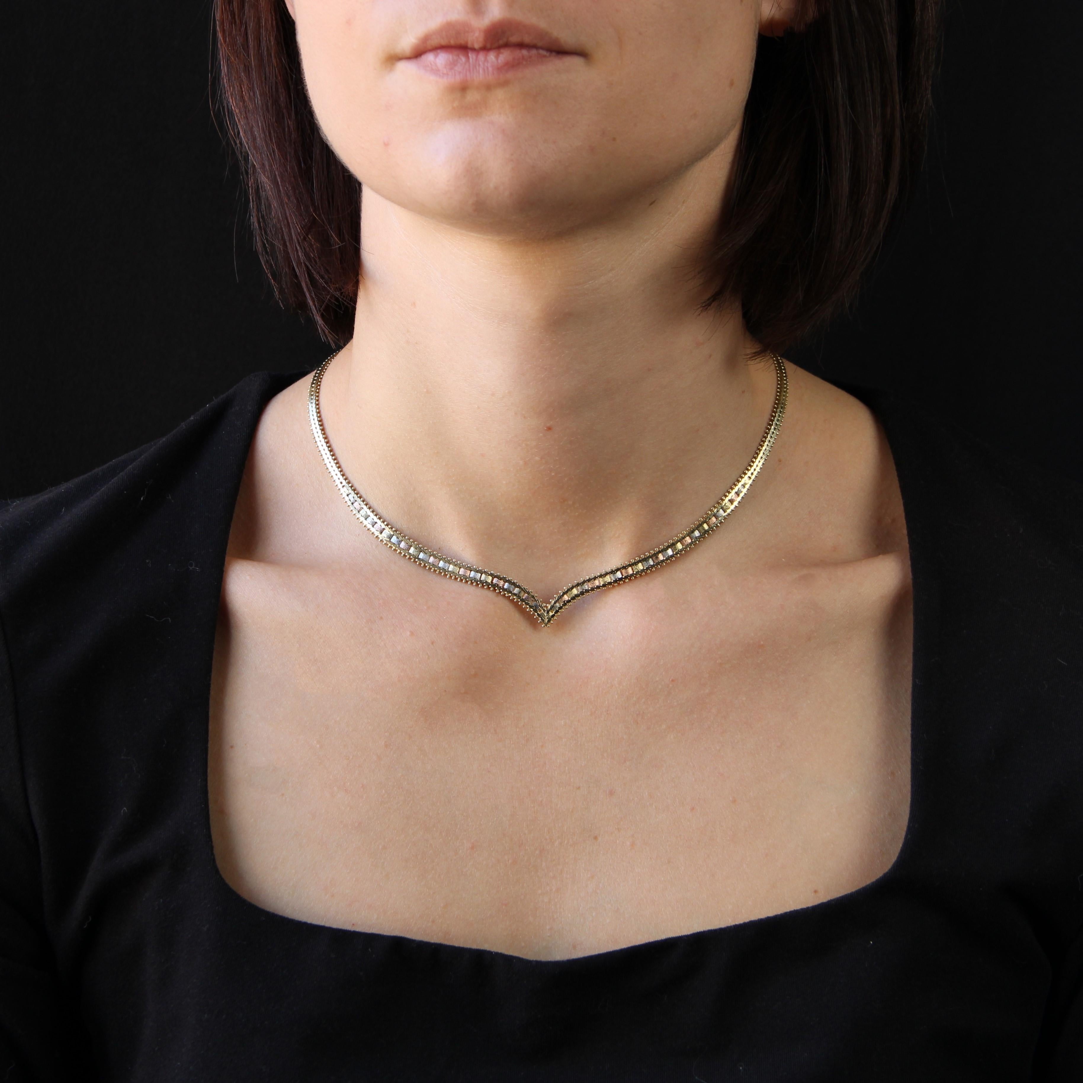 Necklace in 14 karat yellow, rose and grey gold.
This choker necklace features an articulated V-shaped mesh, decorated on the front with alternating 3-color gold clasps and a brushed finish. The mesh forms a V-shape on the front. The clasp is