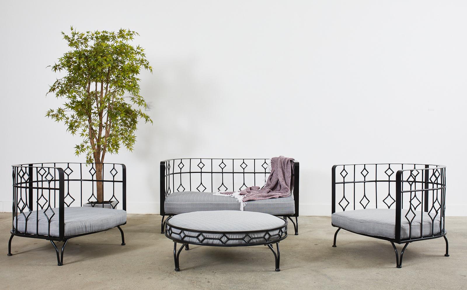 Dramatic post-modern set of four patio and garden furniture suite consisting of two large lounge chairs, one settee, and an ottoman. The set features an iron construction with a black painted finish in a demilune or barrel form frame. The chairs