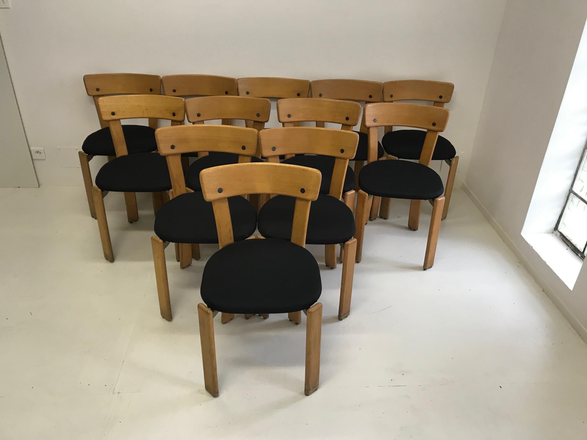 The set of twelve dining chairs was designed by Bruno Rey Switzerland in the 1970s and executed by Dietiker. The dining chairs were made of solid beech and cast aluminum. The seats are newly padded and covered with black textile fabric.