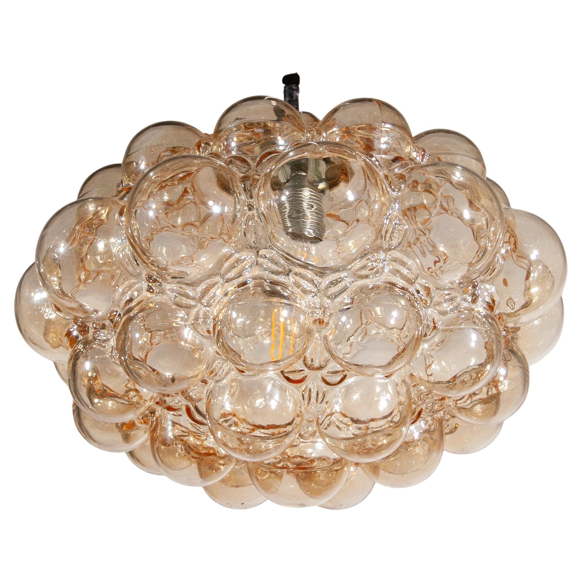 Magnifique lustre, pendentif, en verre bullé de couleur ambre soufflé à la bouche dans un moule conçu par Helena Tynell pour Limburg Glashutte en Allemagne, années 1960.


Helena Tynell est une créatrice finlandaise de verre et de céramique. Elle a