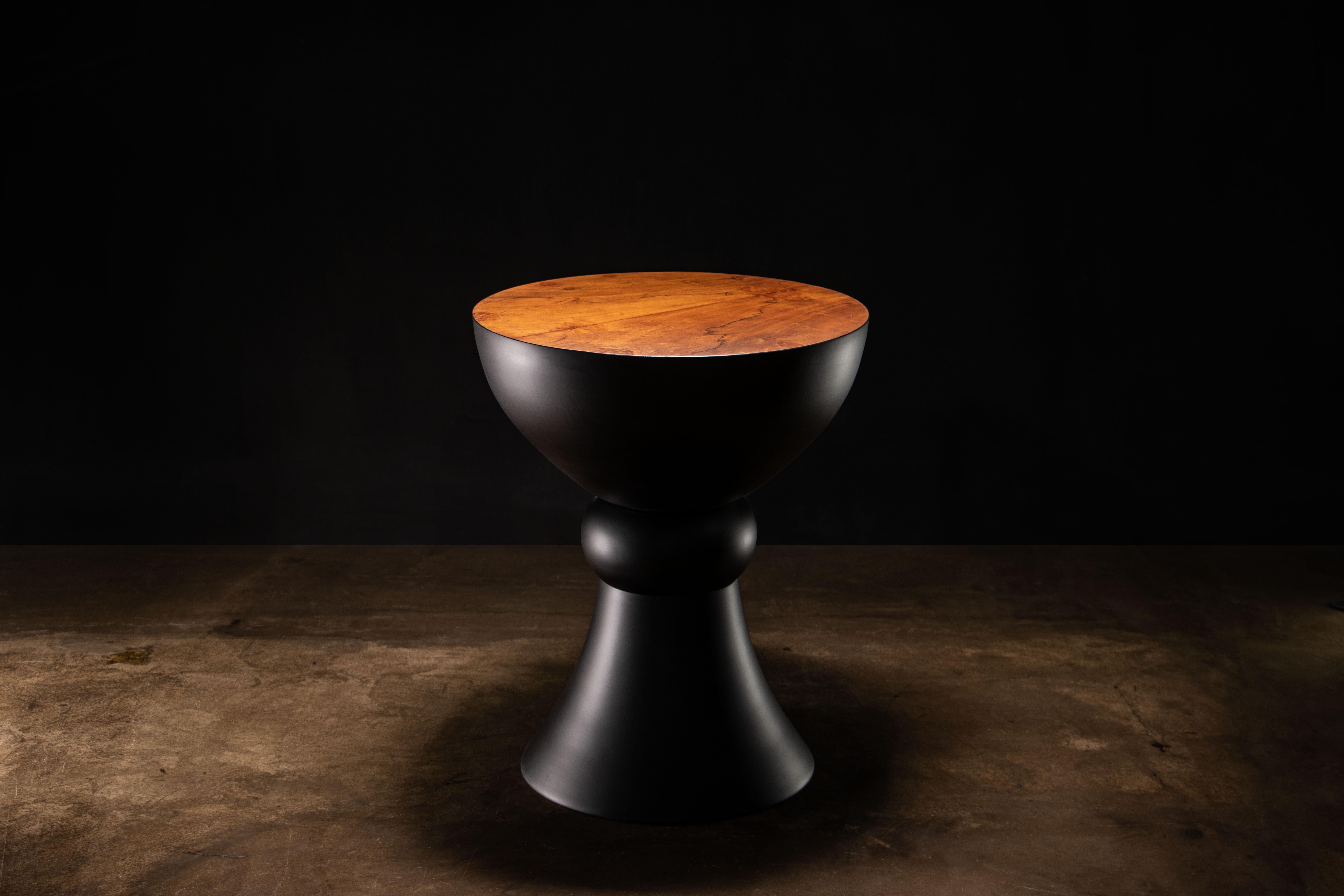 The Caliz occasional table, which can also function as seating, takes its name and its form from the Spanish word for chalice. Shown here in an ebonized finish with a Walnut Burl top.  

Dimensions are 18.5