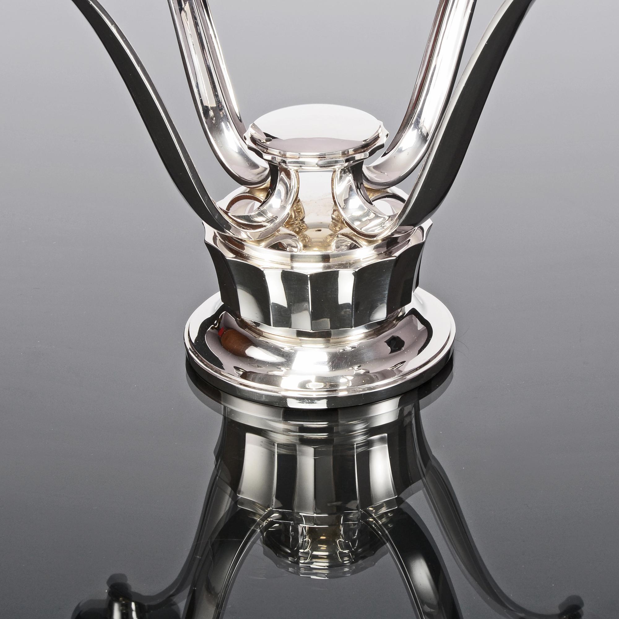 Élégant candélabre moderne en argent fabriqué en 1960 par Asprey & Co, joailliers de la Couronne. La base ronde lambrissée supporte quatre bras élégamment courbés, chacun surmonté d'un bougeoir et d'une lèchefrite en argent. Il s'agit d'une pièce