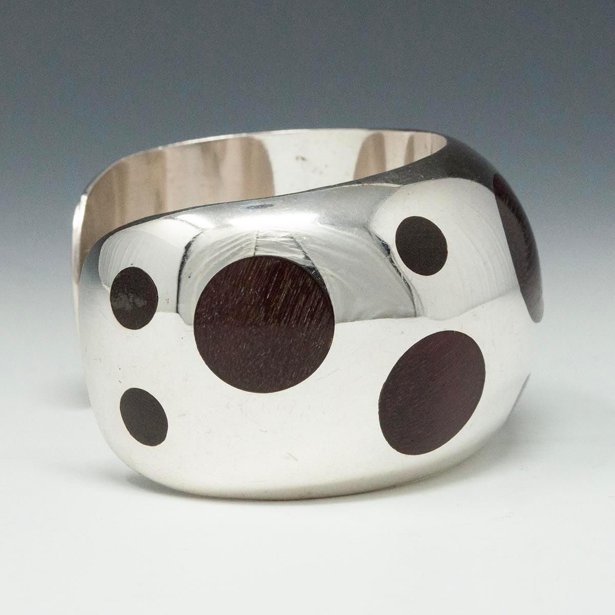 Modern silver and rosewood cuff
A beautiful silver cuff with inlaid rosewood circles, inspired by the 1960s William Spratling design. Marked Mexico 925, it measures 2.5 inches in diameter with a 1-1/8 inch gap. It's 1.5 inches wide, 82 grams.
