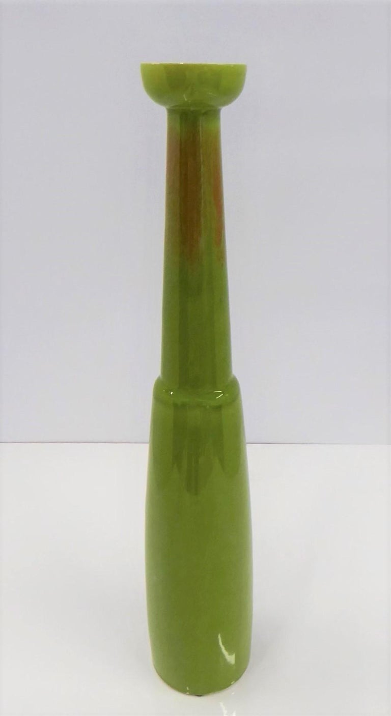 Modern tall slender ceramic vase by Jaru of California from the 1960s. Great body shape with beautiful green tone overall with a splash of orange around the slender neck and lava like overflowing darker green glaze on the waist. With a Jaru paper