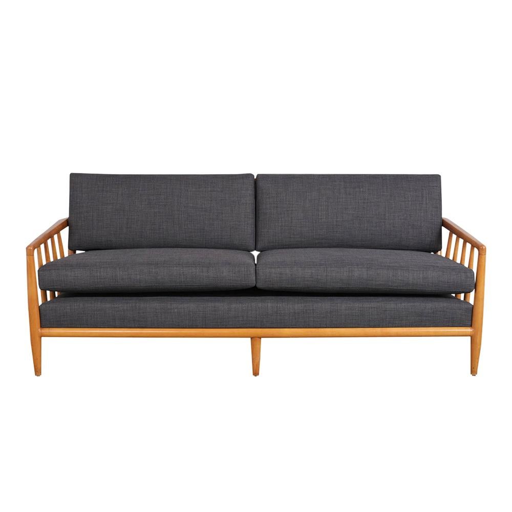 This Mid Century Modern Sofa is designed in the manner of T.H. Robjohn-Gibbings. It features a wood frame with its original natural walnut color stain and lacquered finish. It also has carved armrests & legs accentuated by the simple cushion on the