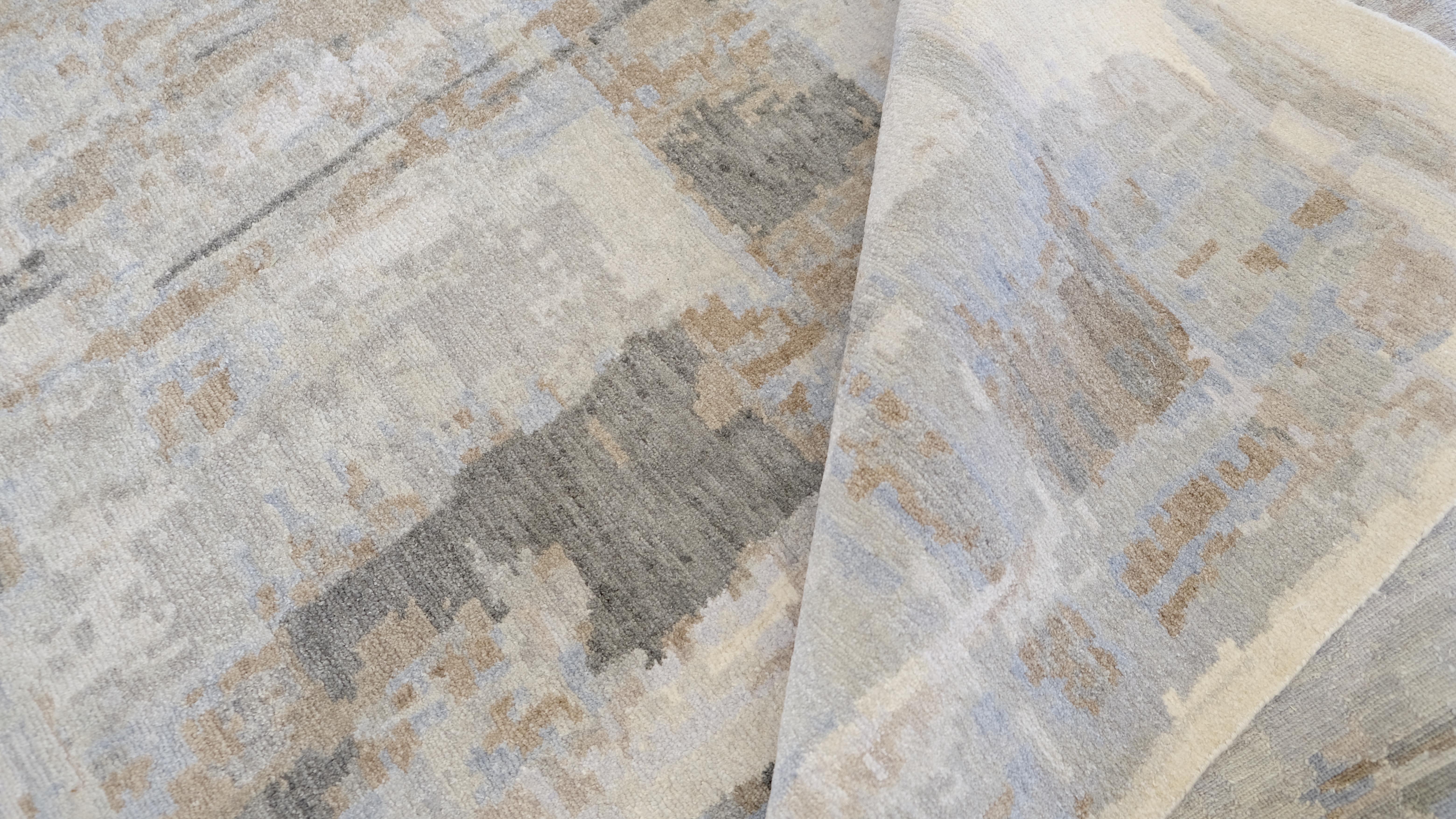 Bringen Sie zeitgenössische Eleganz in Ihr Zuhause mit diesem exquisiten handgeknüpften Teppich aus Wolle und Seide. Das Design zeigt ein raffiniertes, abstraktes, geometrisches Muster in ruhigen, sanften Blau-, Grün-, Grau-, Braun- und
