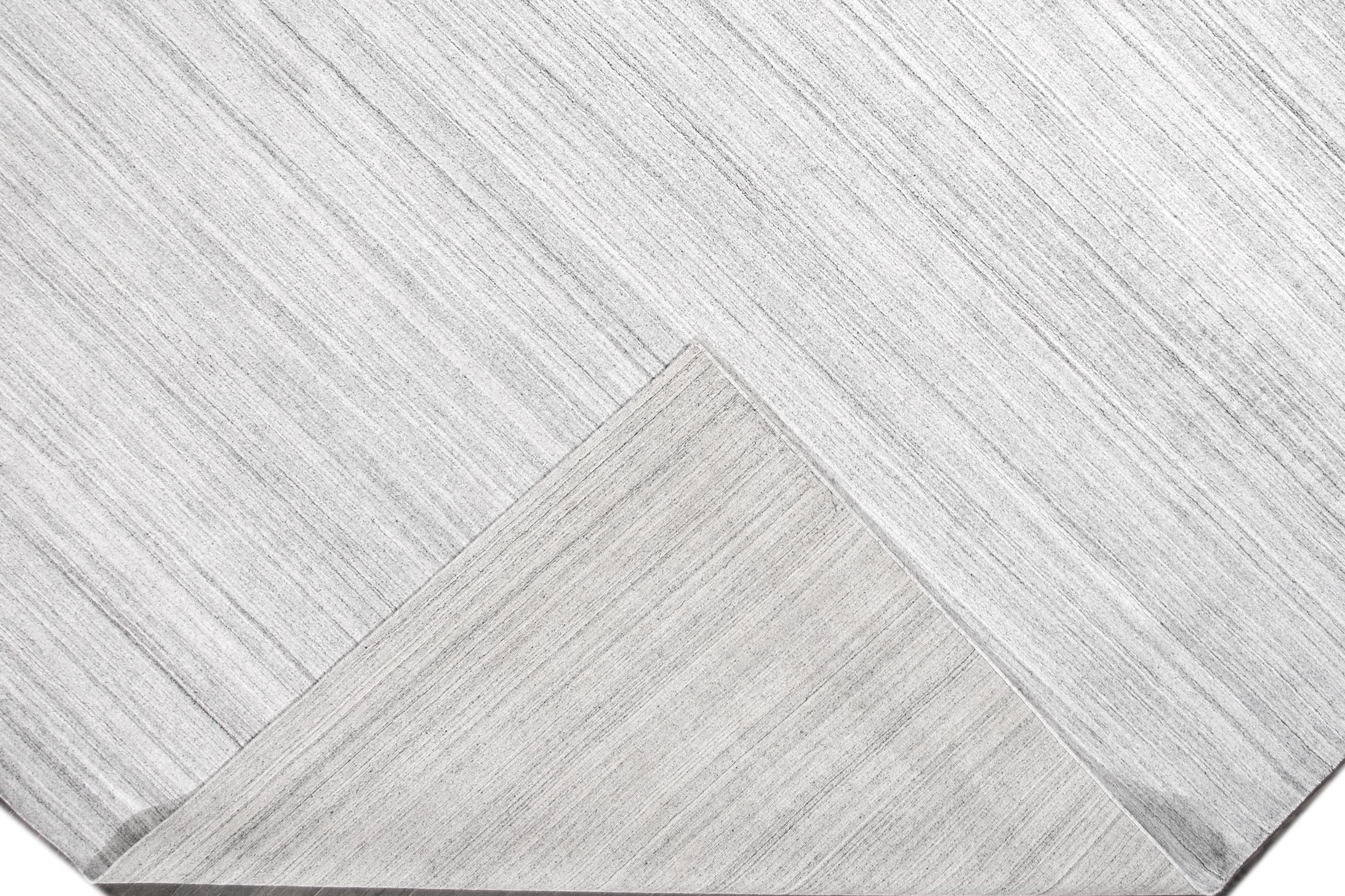 Ein moderner, handgewebter Übergangsteppich mit einem durchgängig grauen Motiv. Dieses Stück wäre die perfekte Ergänzung für Ihr Zuhause. Dieser Teppich misst 12'2