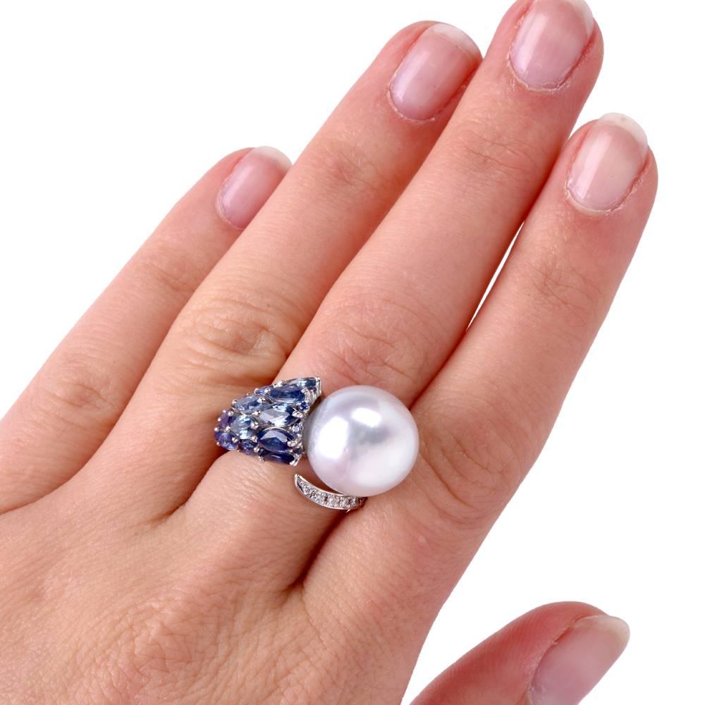 This aesthetically absorbing estate cocktail ring of avant-garde design exposes a lustrous 14 mm South Sea pearl of an enchanting silver-white with a subtle light pinkish hue color.  The14 marquise sapphires range in color between light to