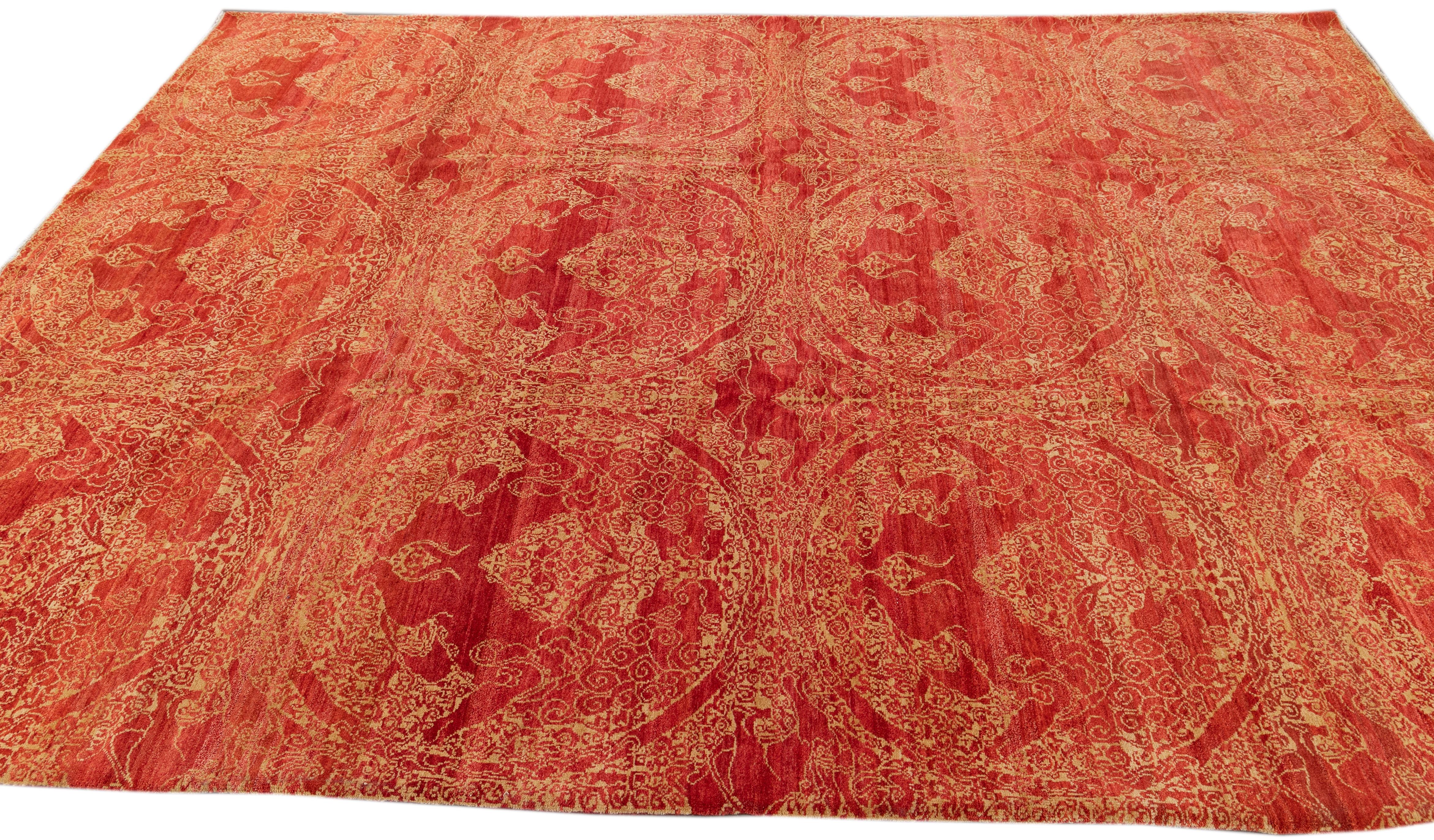 This hand-knotted wool rug exemplifies contemporary design with its captivating red foundation beautifully contrasted by sophisticated beige accents arranged in an exquisite medallion pattern throughout. Meticulously crafted with meticulous