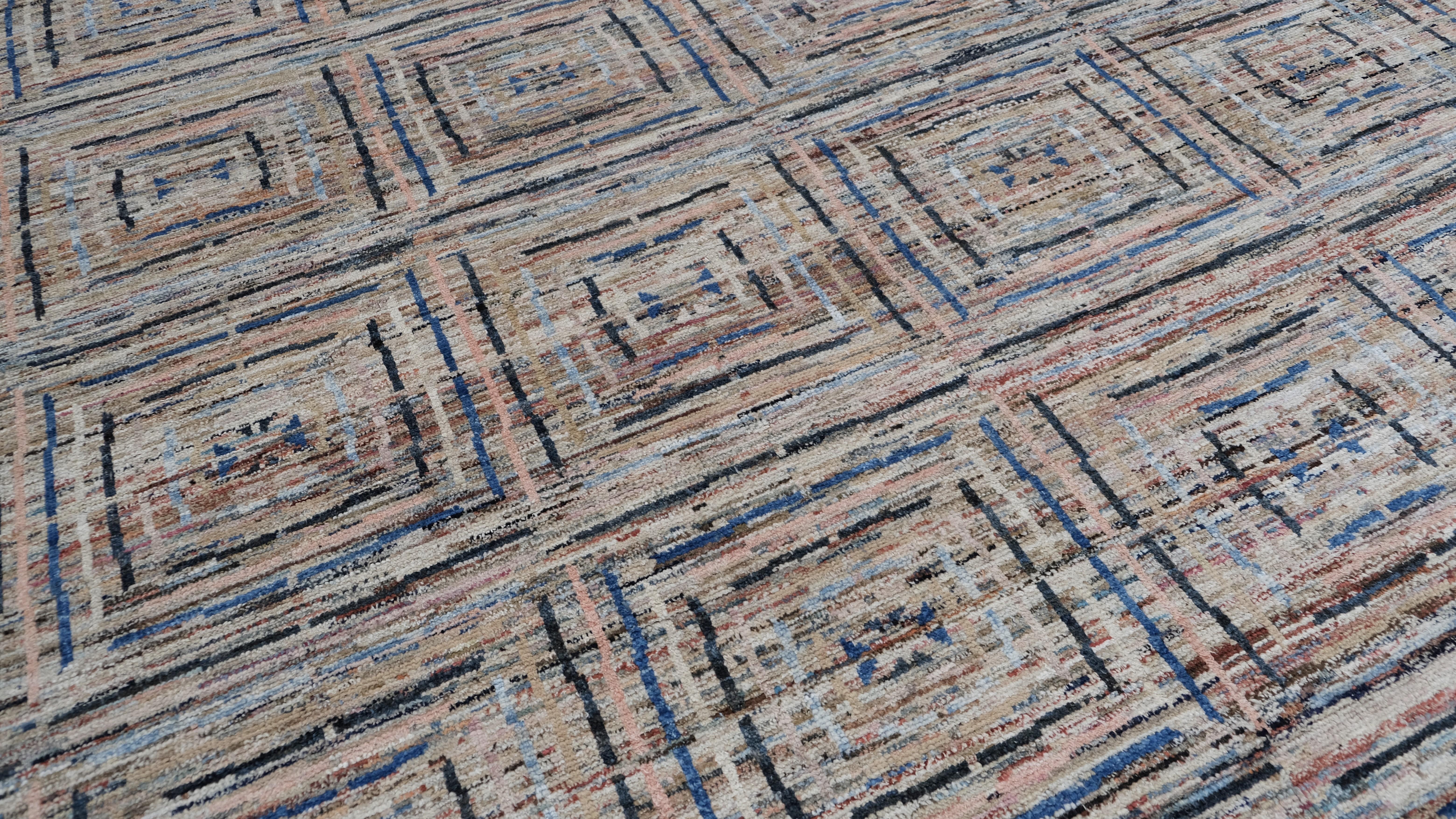 Dieser exquisite, handgeknüpfte Wollteppich zeigt ein faszinierendes geometrisches Muster mit einem dynamischen Zusammenspiel von Farben und Texturen. Die filigranen, mit Präzision gewebten quadratischen Motive schaffen eine beeindruckende visuelle