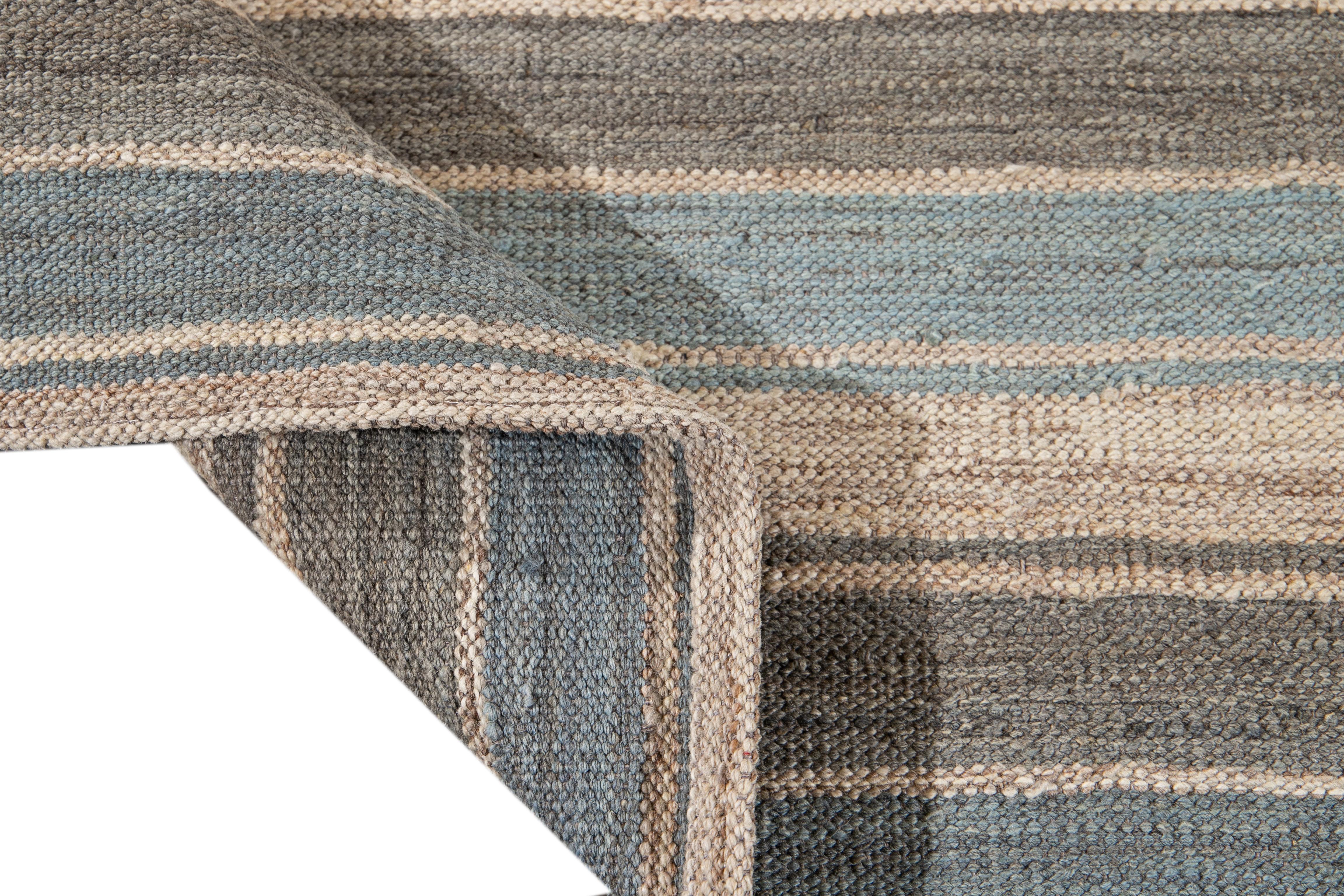Beautiful modern flat-weave Kilim hand knotted wool rug. This rug has a field of a blue, gray, and beige color in a gorgeous all-over geometric stripe design.

This rug measures 8' 10