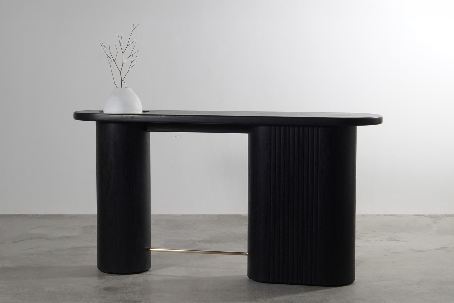 The Meson Console Table is a striking embodiment of contemporary design, where bold forms meet meticulous craftsmanship. Its unique silhouette, defined by two robust cylindrical legs supporting a sleek, elongated tabletop, instantly commands