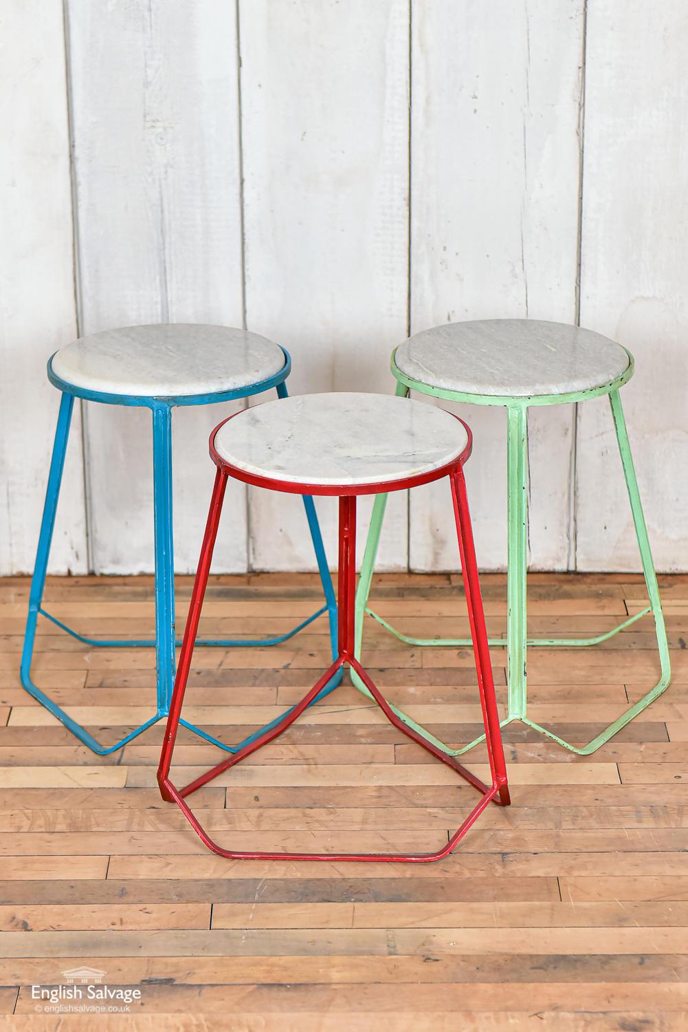 Attractive modernist or midcentury style steel three-cornered stools with marble seats, available in red, green and blue. The paint has a distressed look with some chips and scratches, lending an appealing weathered appearance.