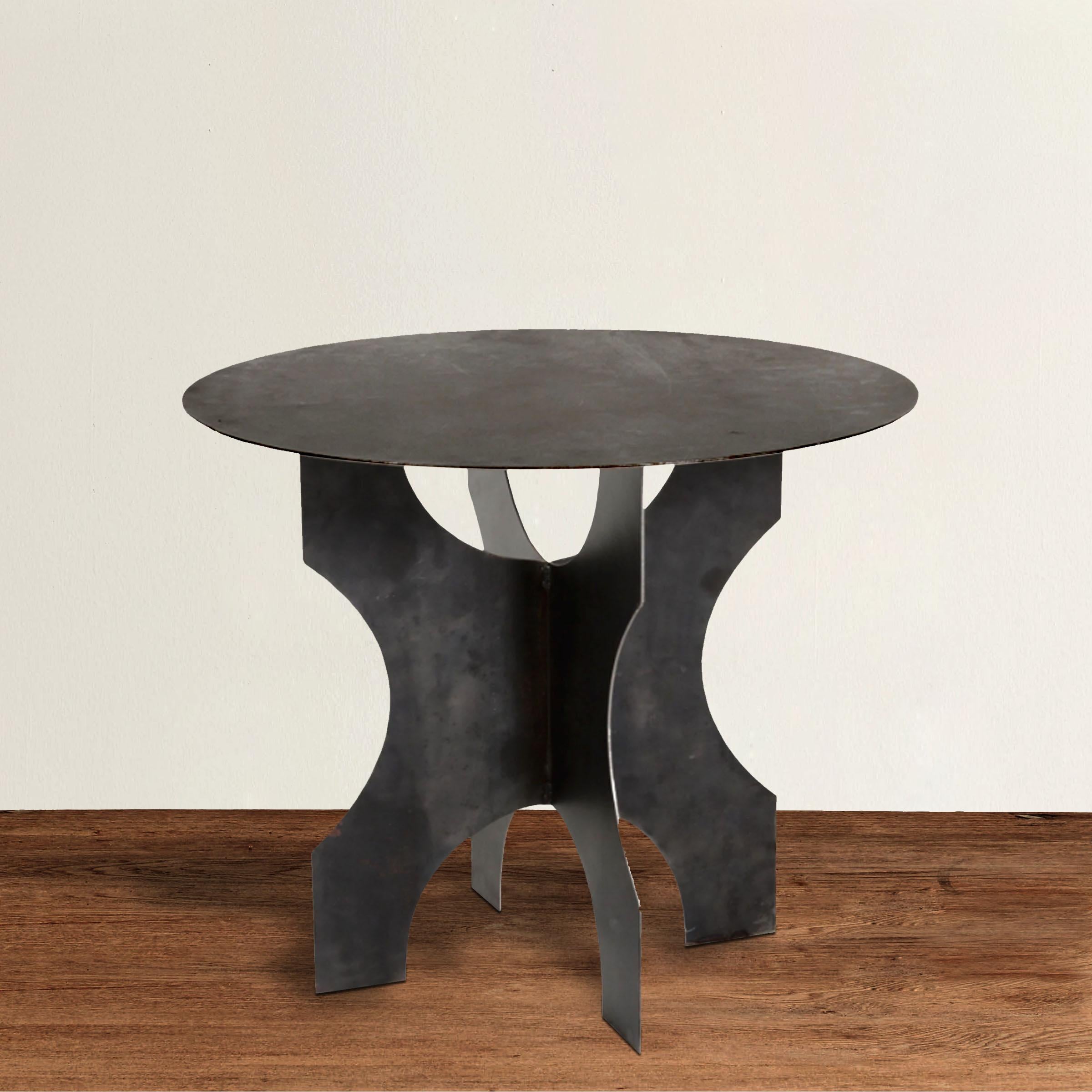 An uber chic modern steel round table with a Brutalist attitude, constructed with four legs welded together under a round top.