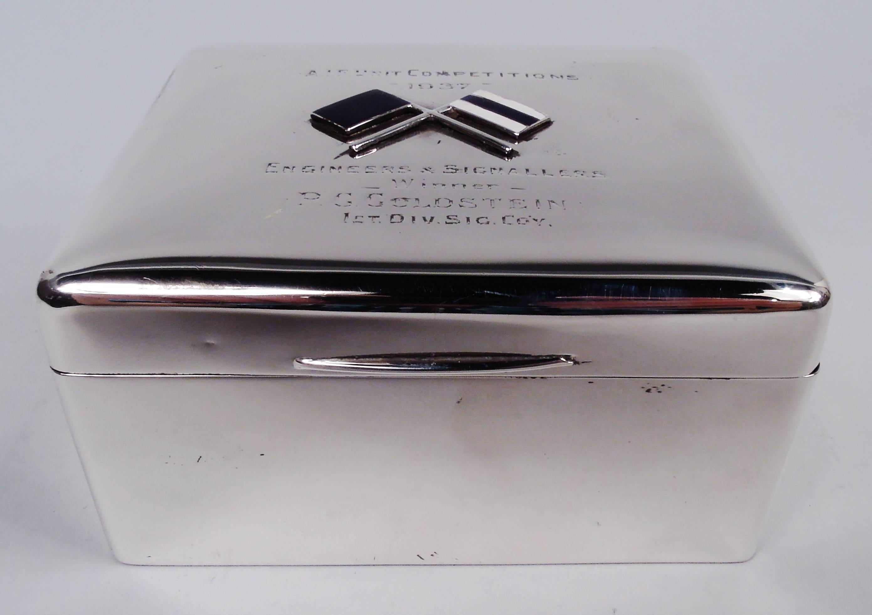 Caja moderna de plata de ley, hacia 1935. Rectangular con lados rectos y esquinas curvadas. Tapa articulada con lengüeta cónica. Interior forrado de cedro y parte inferior forrada de cuero.

En la cubierta superior presentación grabada: 