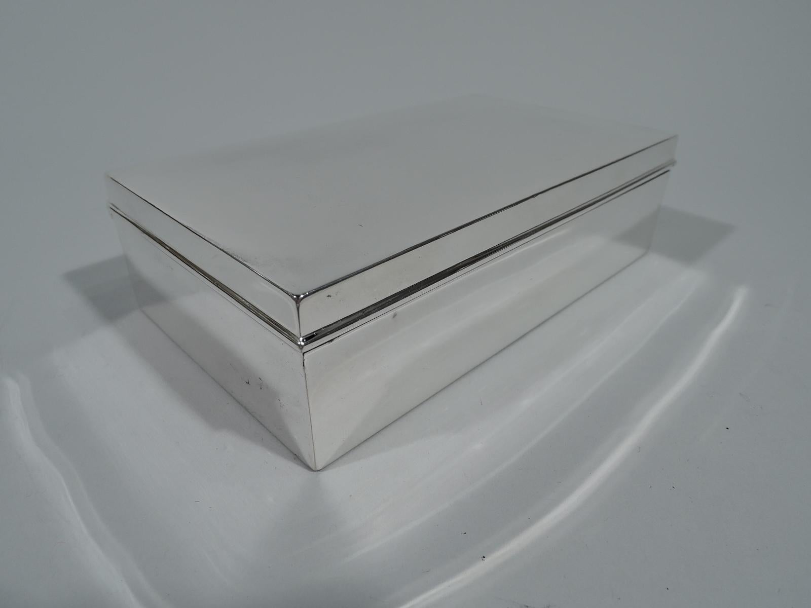 Modern sterling silver box. Made by Tiffany & Co. in New York. Rectangular with straight sides. Cover hinged and gently curved with molded rim. Box interior cedar lined. Cover interior gilt. Hallmark includes pattern no. 19572 (first produced in
