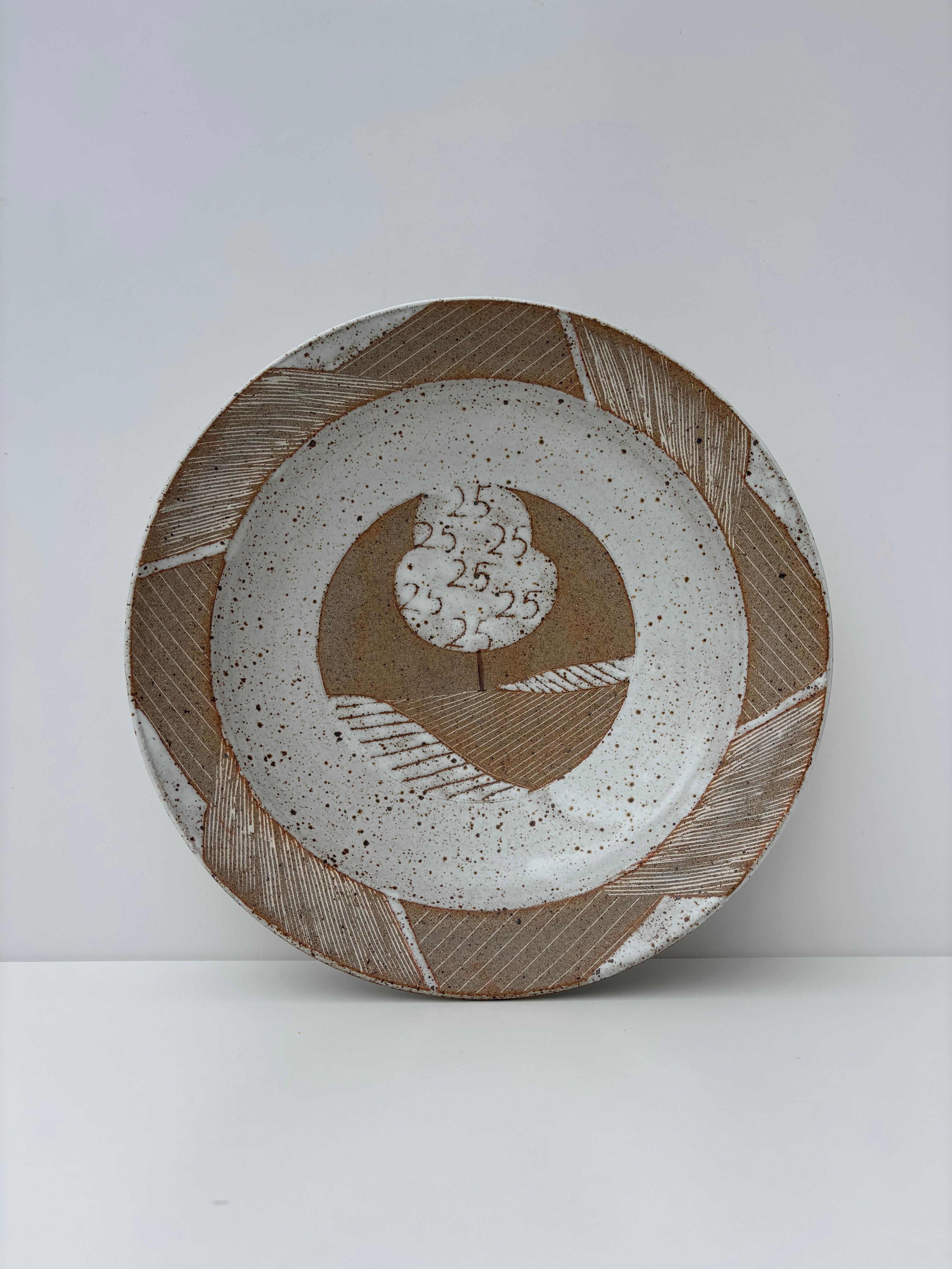 Modernist stoneware centerpiece bowl by Kähler Keramik in 1988. Light gray spotted glaze and unglazed sandcolored ceramic material side by side in lined graphic patterns. 
To be used as serveware, centerpiece or as wall decoration.
Beautiful vintage