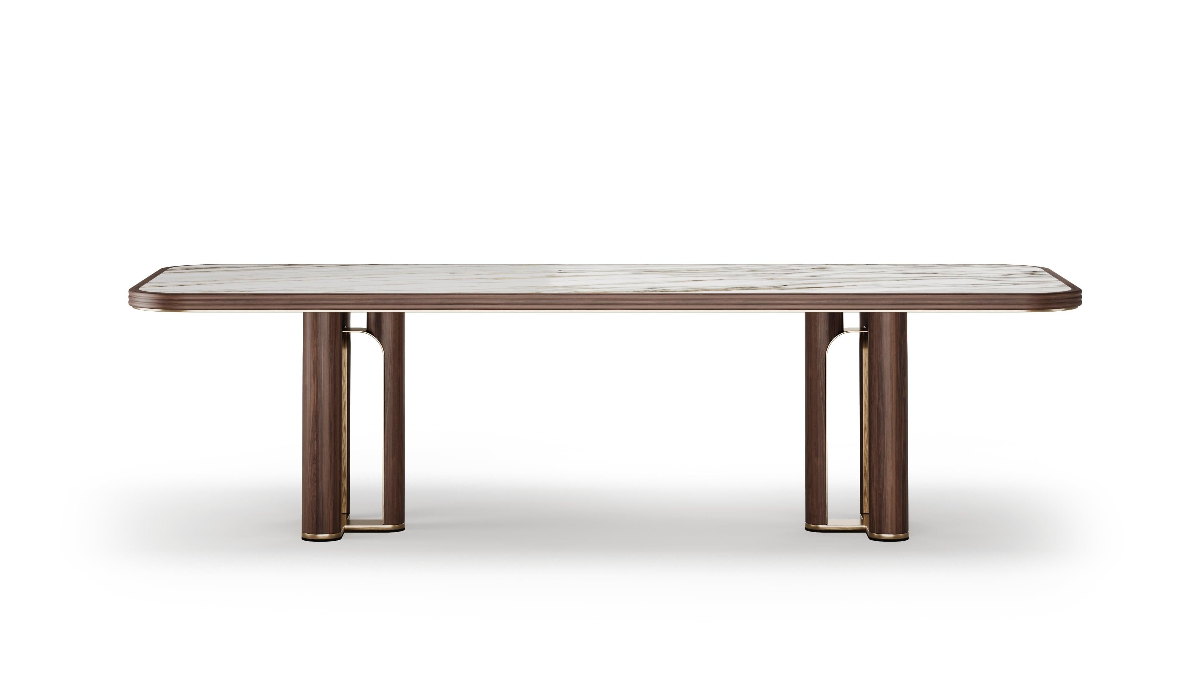 Rich in character, the Strato dining table is defined by bold lines and noble materials. A brass connector joins the walnut wooden legs, creating a striking yet refined base structure. The Calacatta Gold marble top adds contrast and depth with its